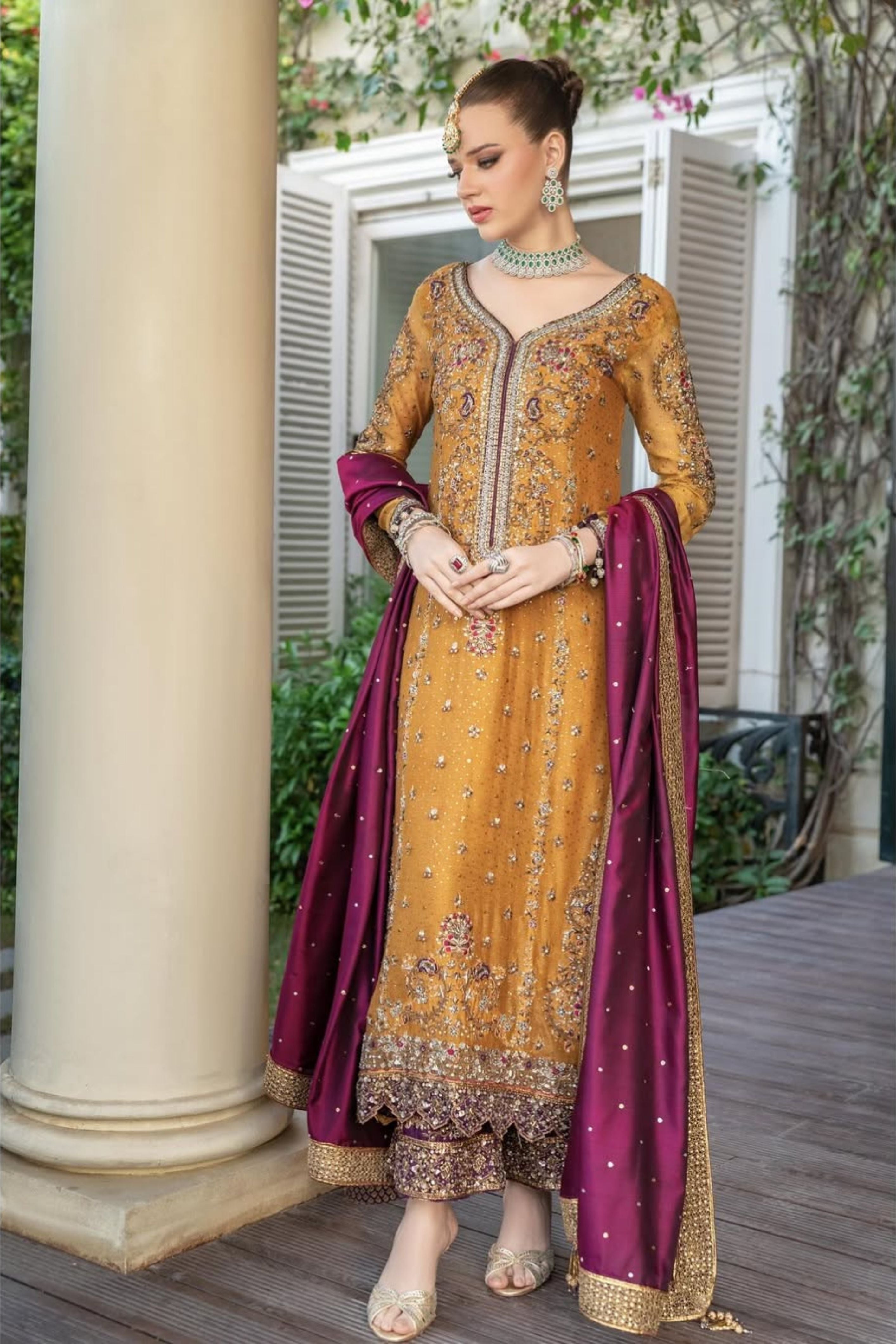 Woman in a traditional outfit with a yellow and purple dress standing outdoors.
