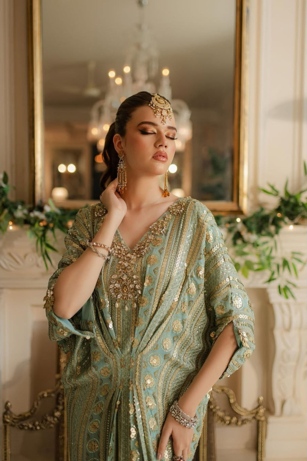Woman in a green and gold dress with jewelry in an elegant interior setting