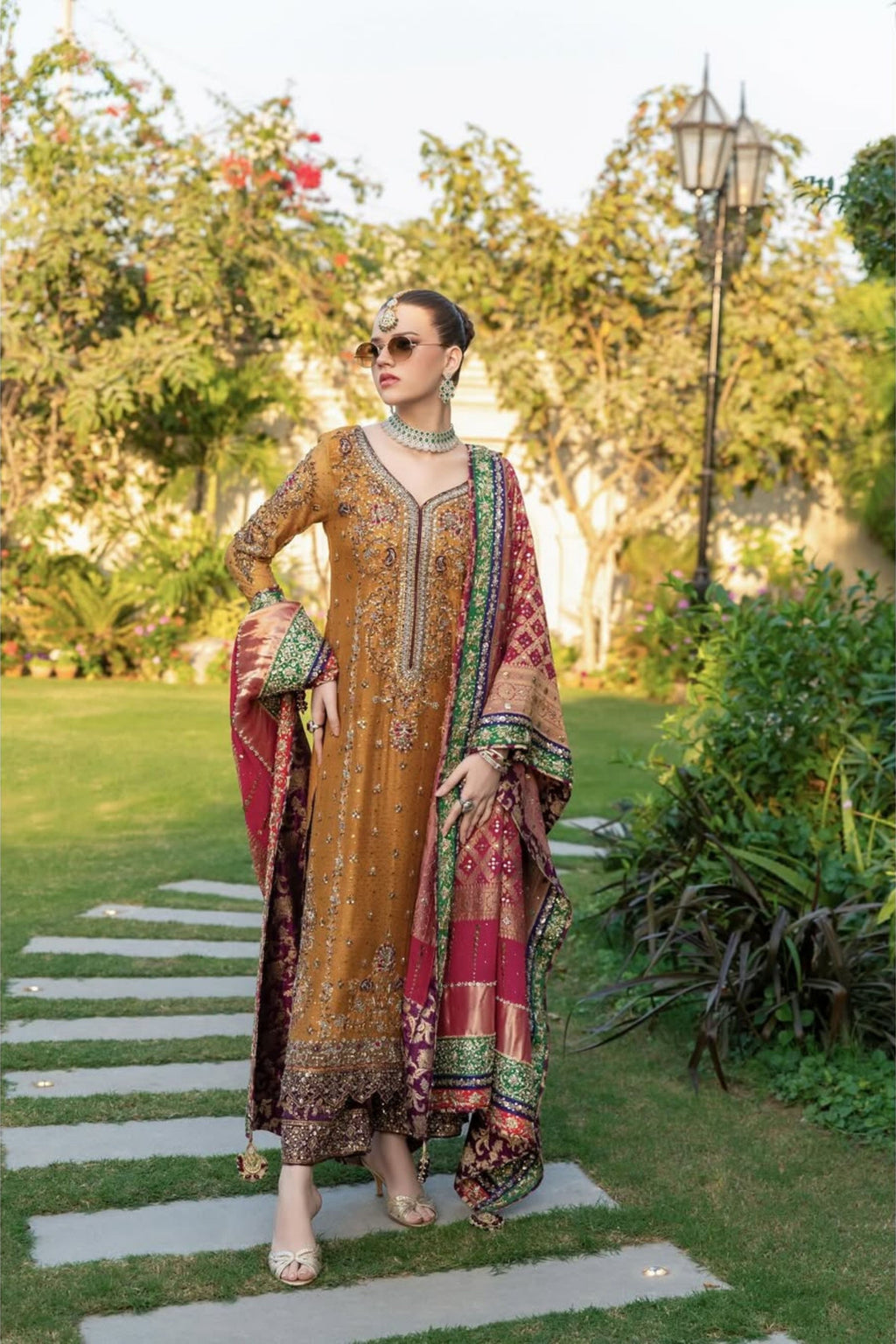 Woman in traditional embroidered outfit standing in a garden