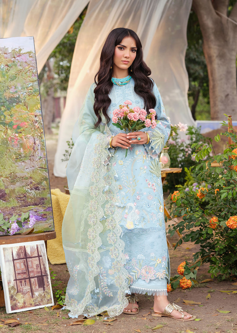 Woman in a light blue embroidered dress holding flowers in an outdoor setting with art and plants.