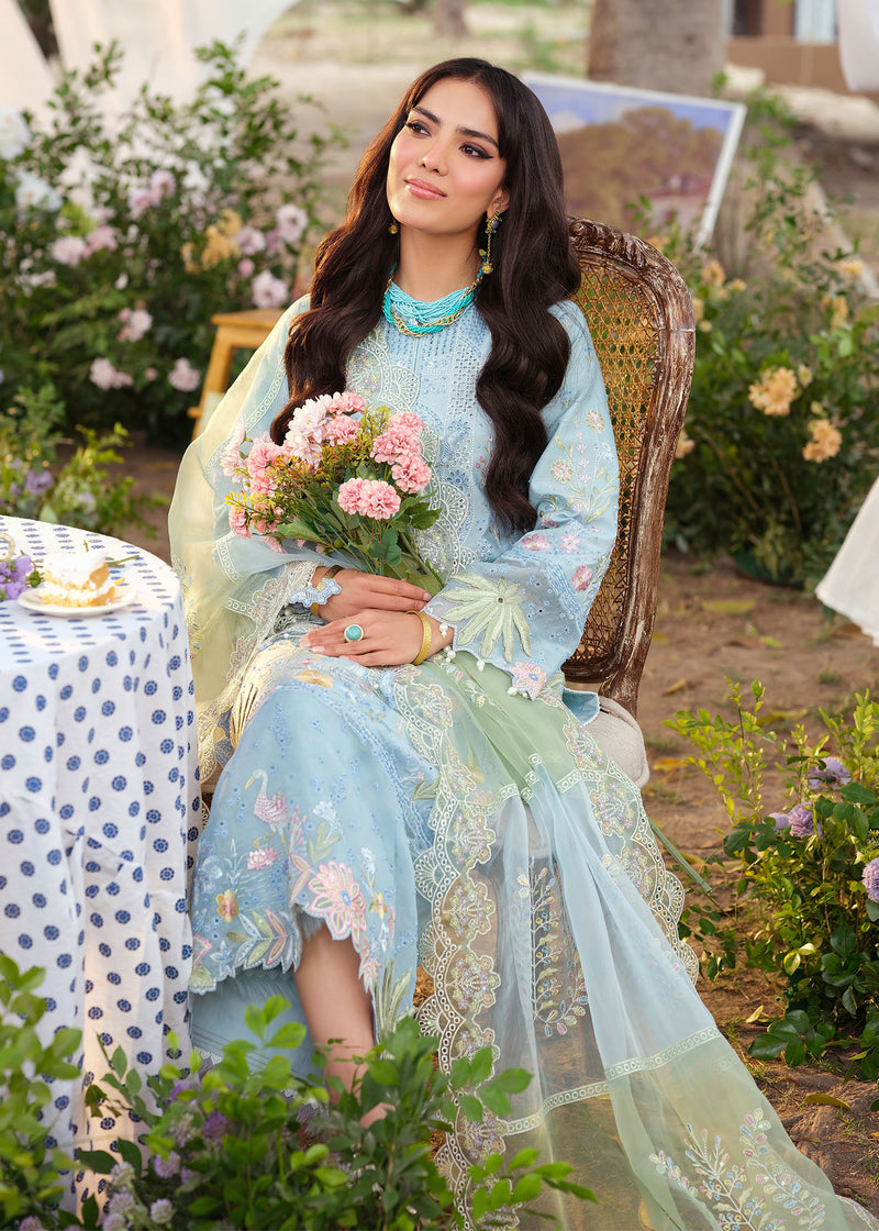 Woman in a light blue embroidered outfit holding flowers in a garden setting