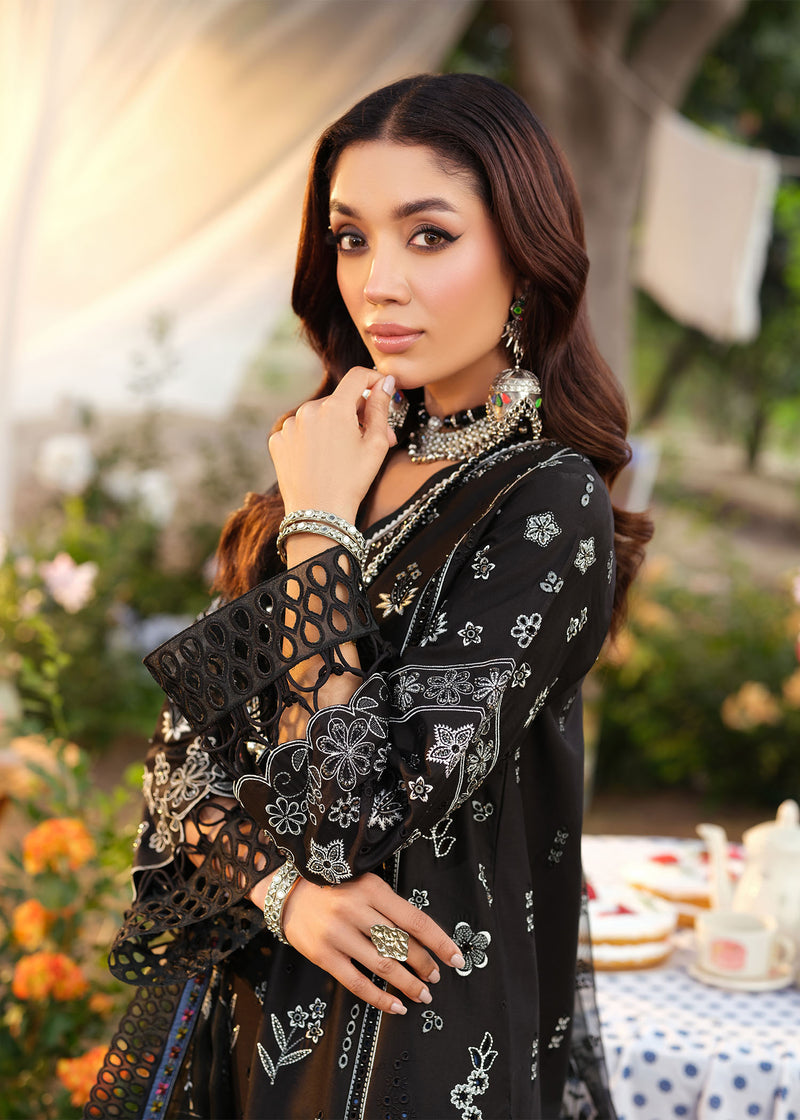Woman in an embroidered black outfit with jewelry in a garden setting
