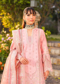 Woman in a pink embroidered outfit standing outdoors with greenery in the background