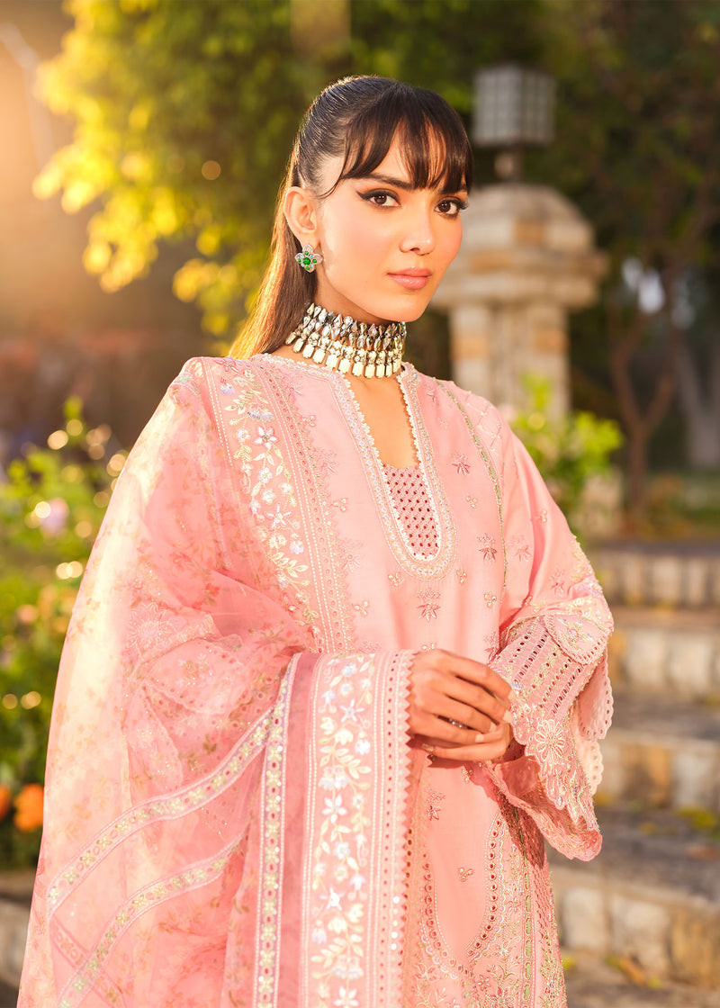 Woman wearing a pink embroidered outfit with a scenic background