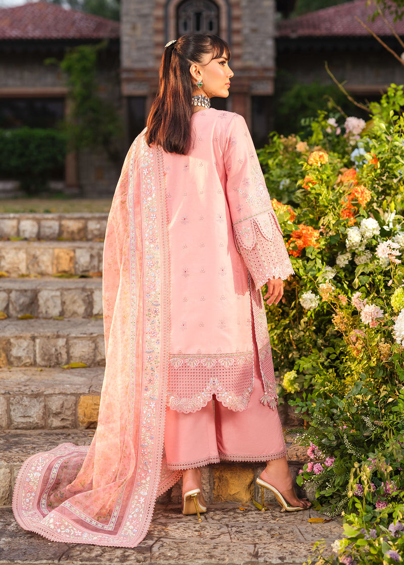 Woman in a pink traditional outfit standing outdoors with flowers and steps in the background