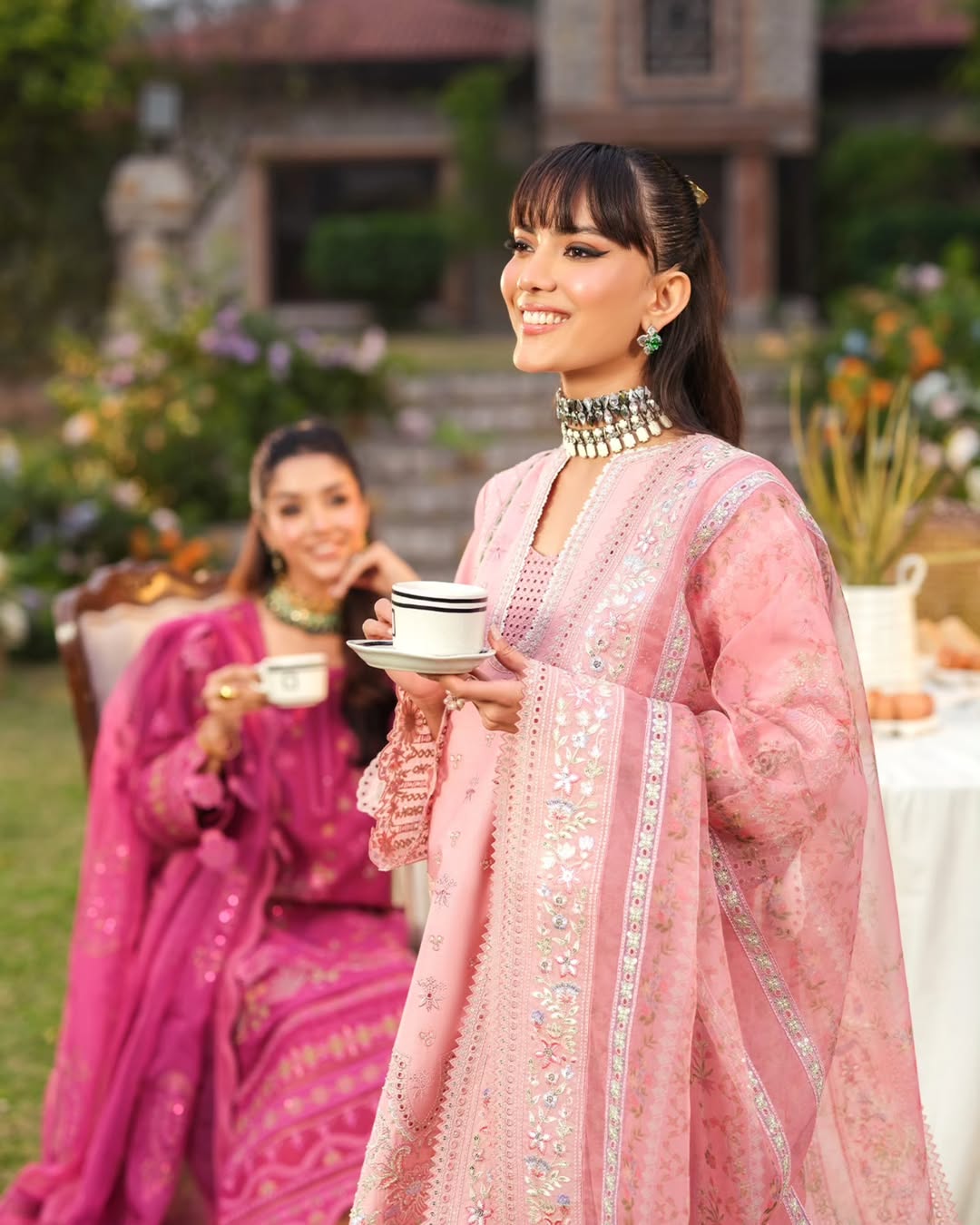Woman in a pink traditional outfit holding a cup outdoors