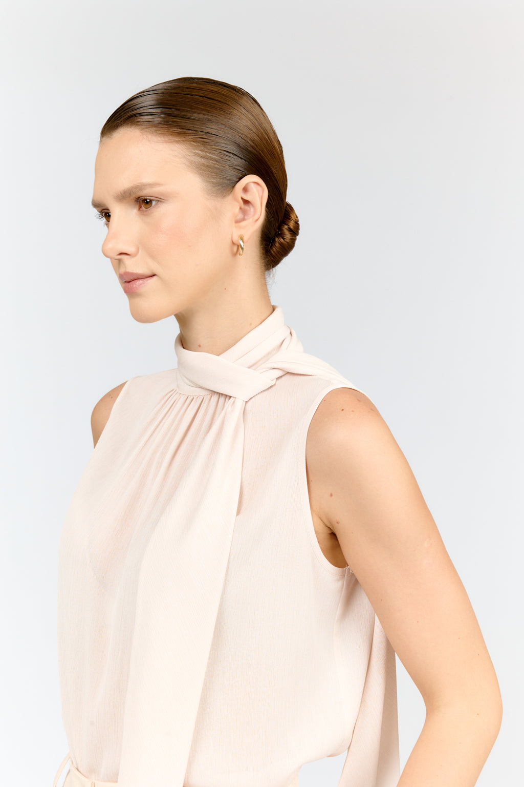 Woman wearing a light pink sleeveless top against a white background