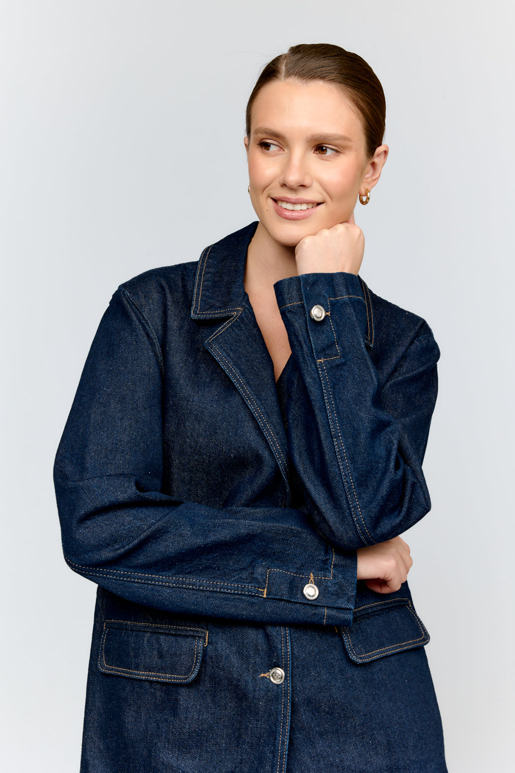 Woman wearing a dark blue denim jacket on a light gray background