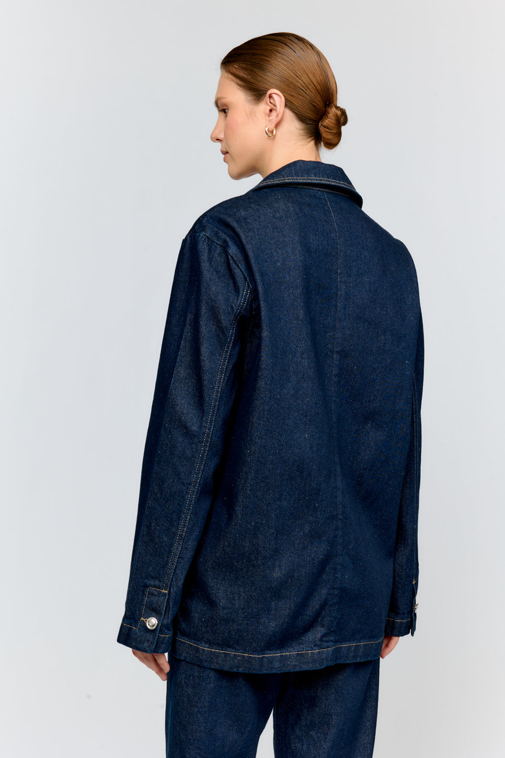 Person wearing a blue denim jacket on a light gray background