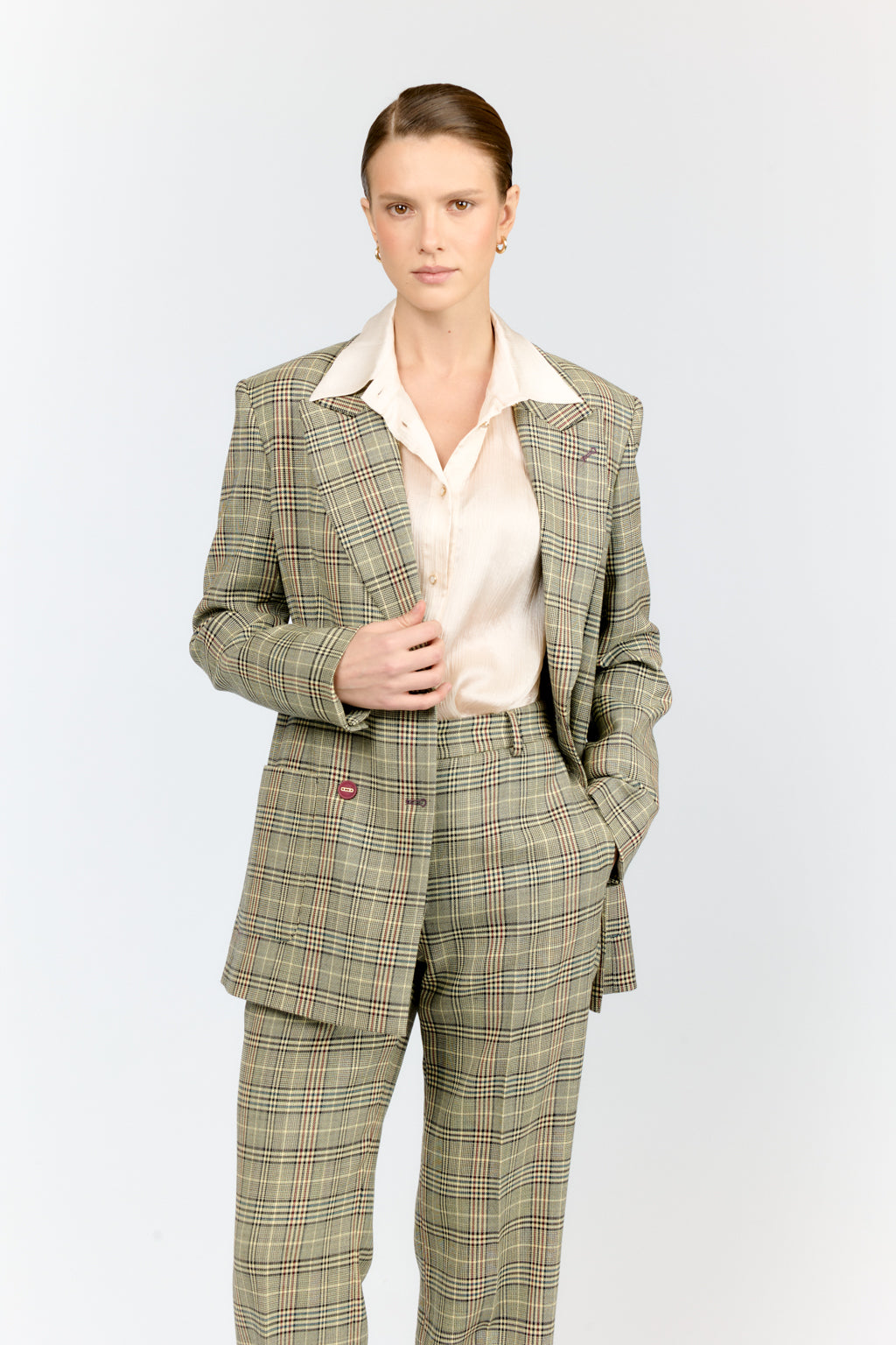 Woman wearing a green plaid suit with a white shirt on a white background