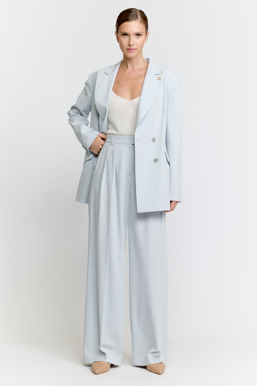 Woman wearing a light blue suit with a white top on a white background