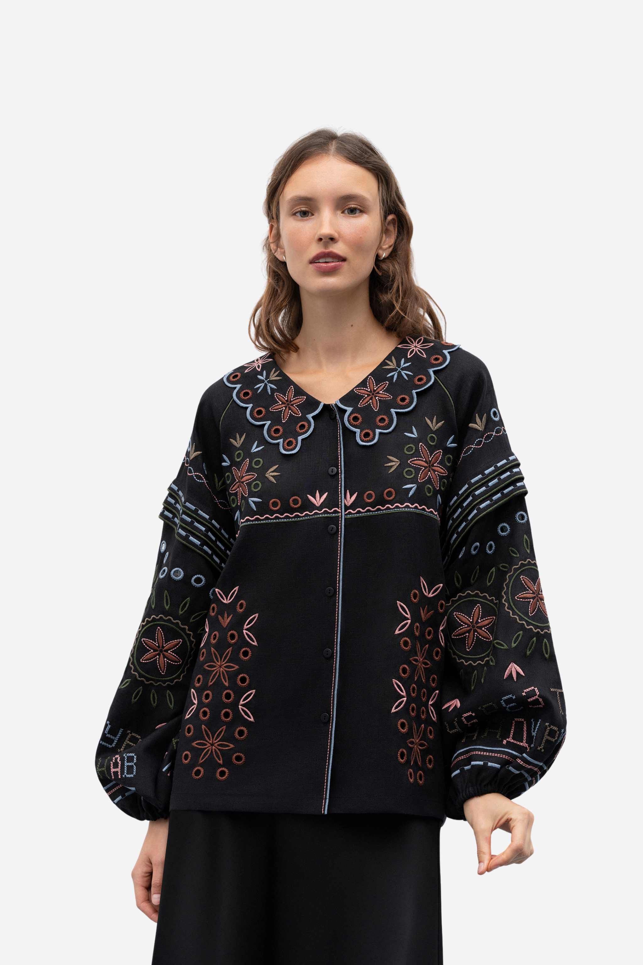 Woman wearing a black embroidered blouse on a white background