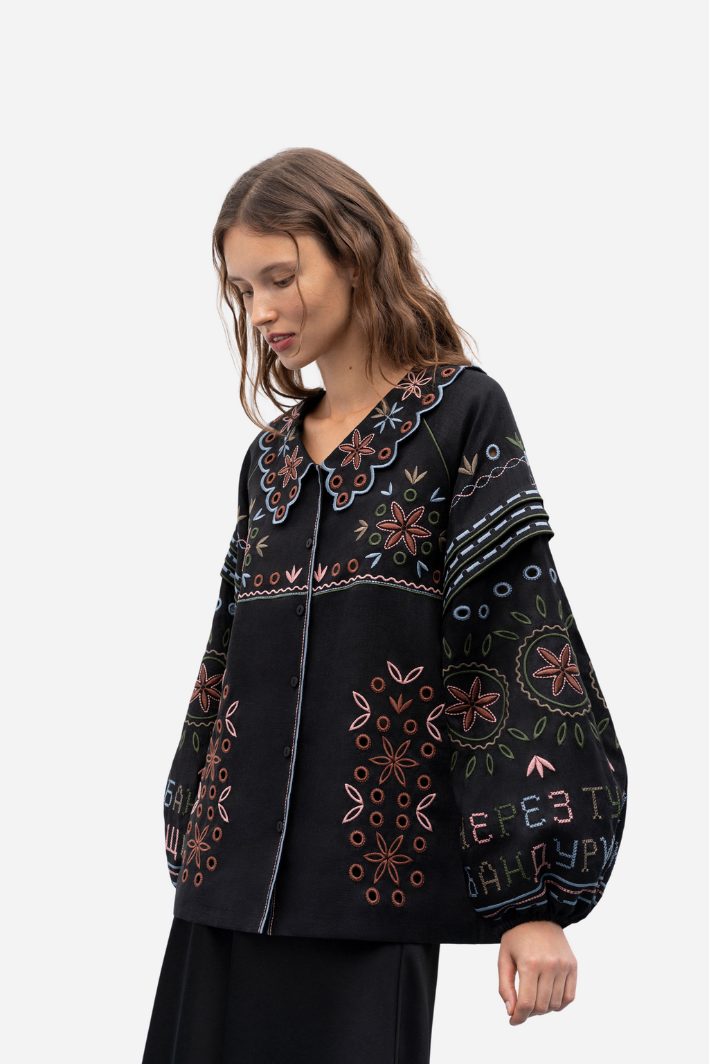 Woman wearing a black cardigan with colorful floral patterns on a white background