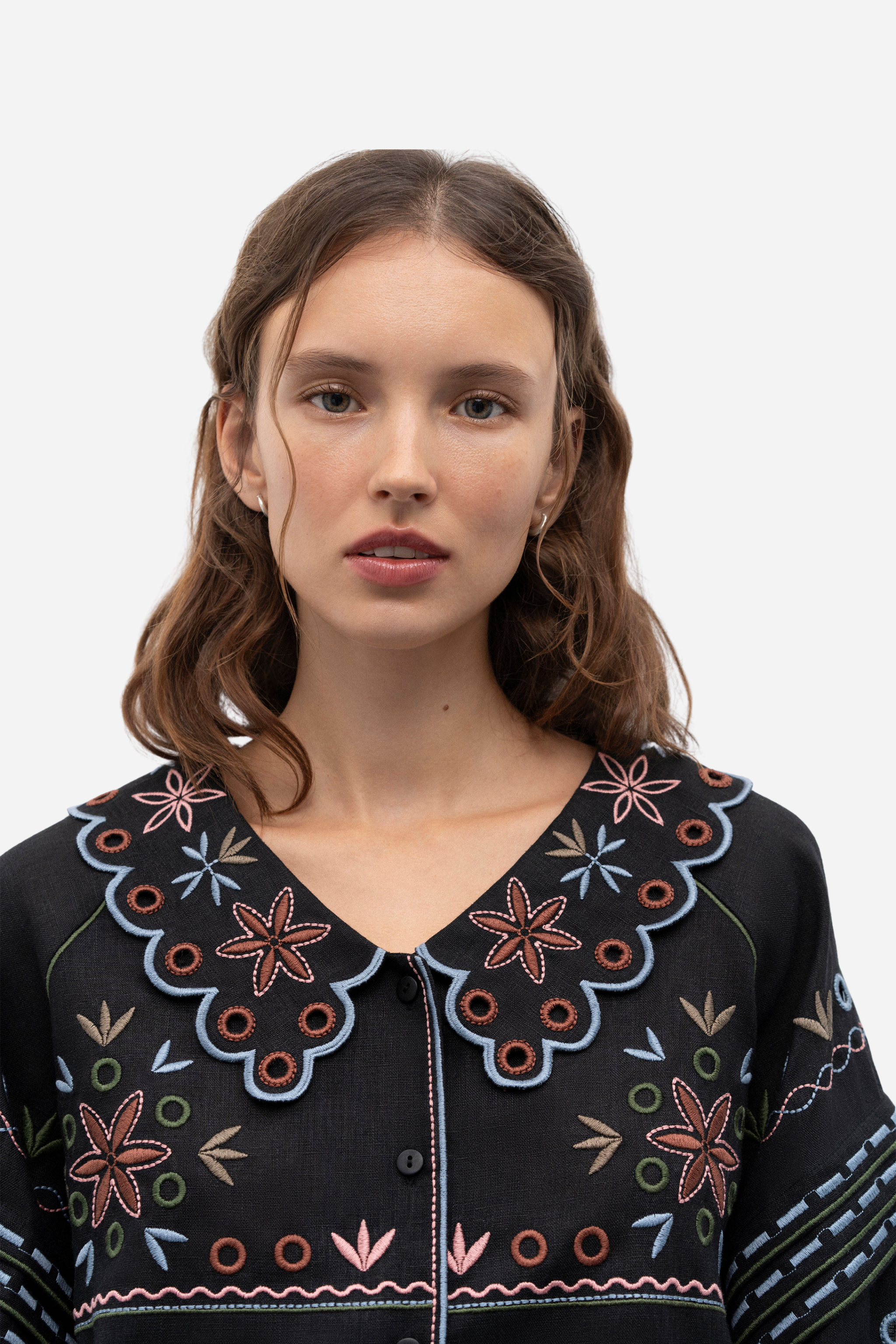 Woman wearing a black embroidered blouse against a white background