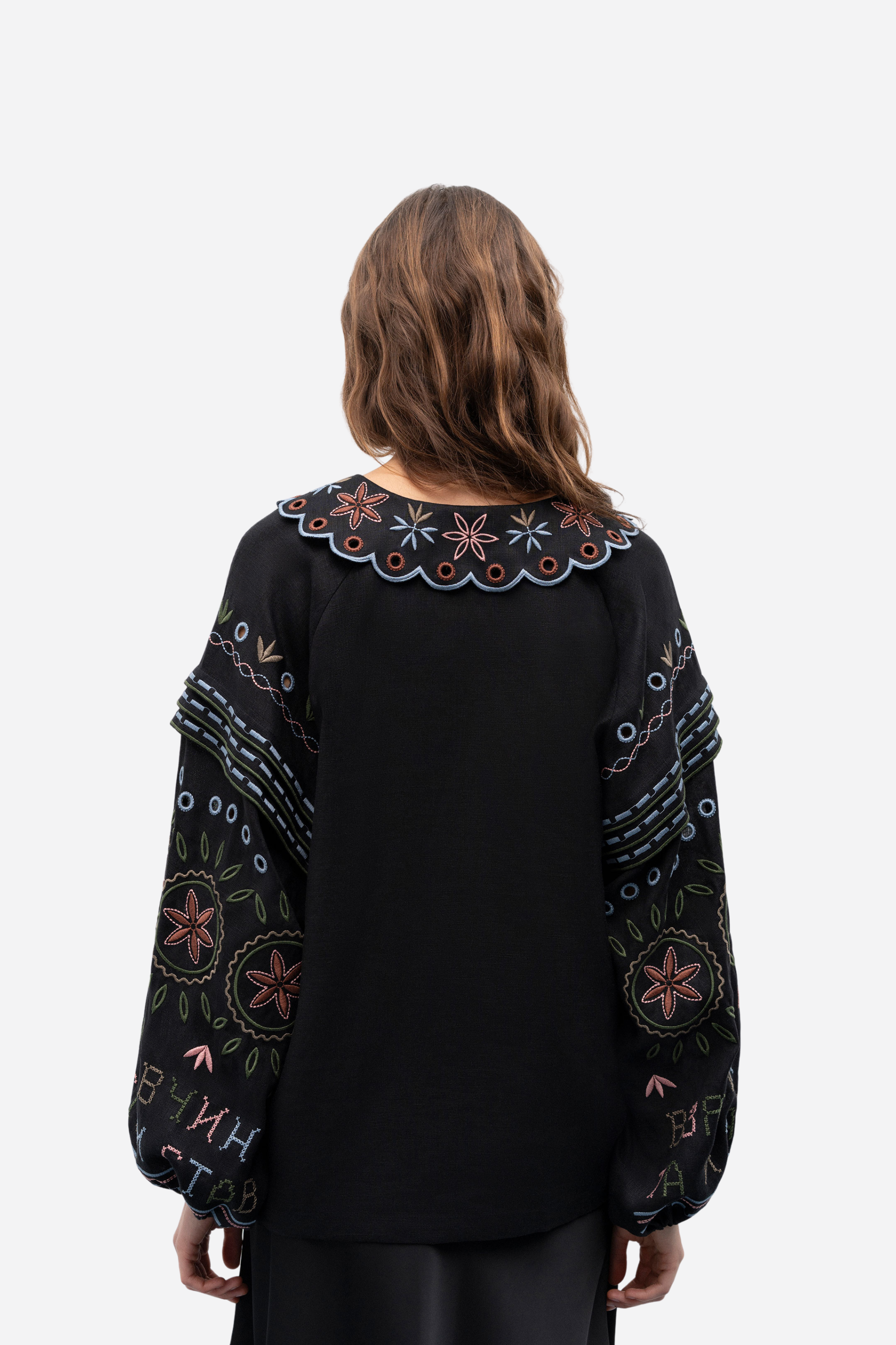 Black embroidered blouse worn by a person on a white background