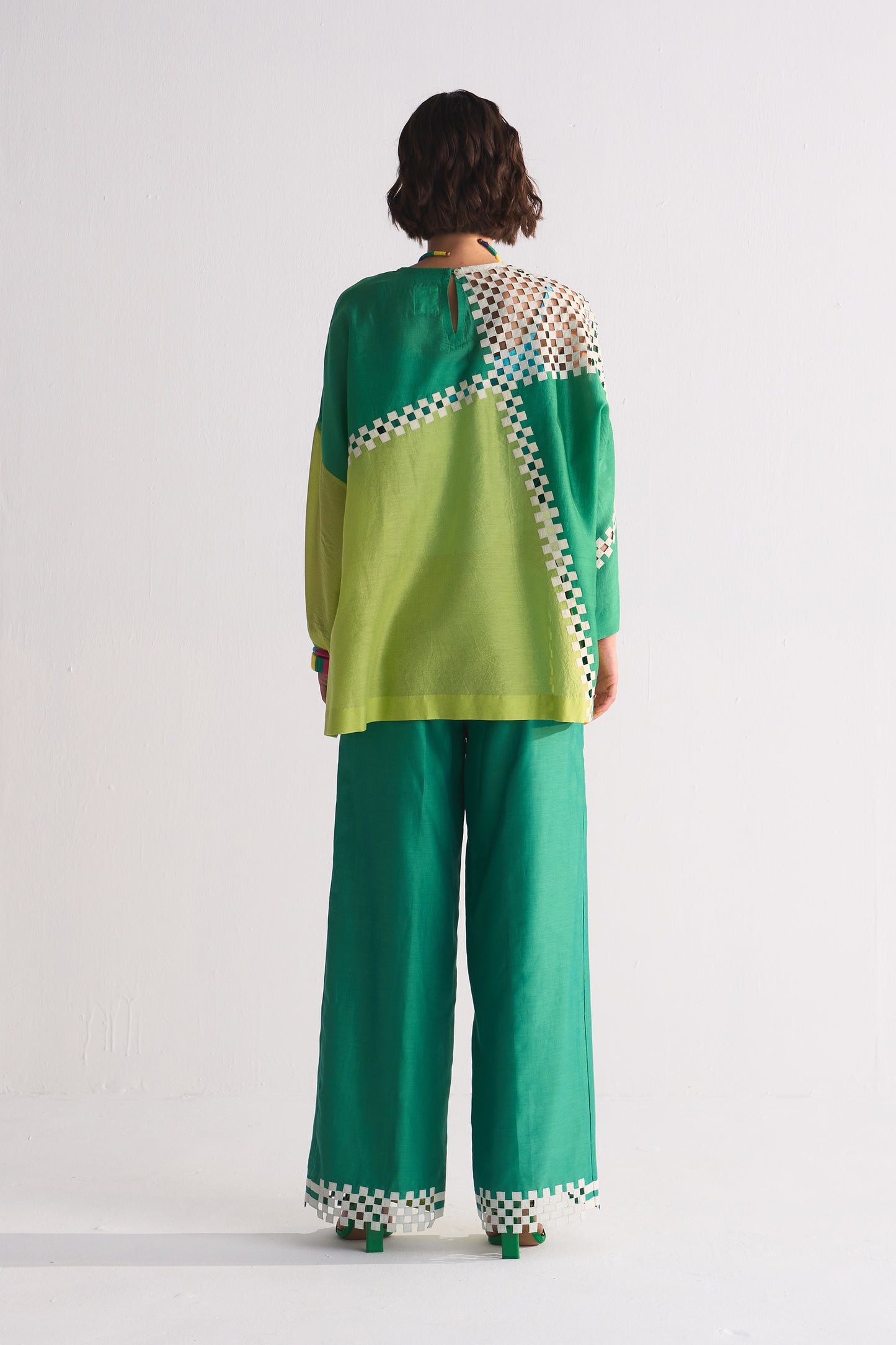 Person wearing a green and white patterned outfit on a white background