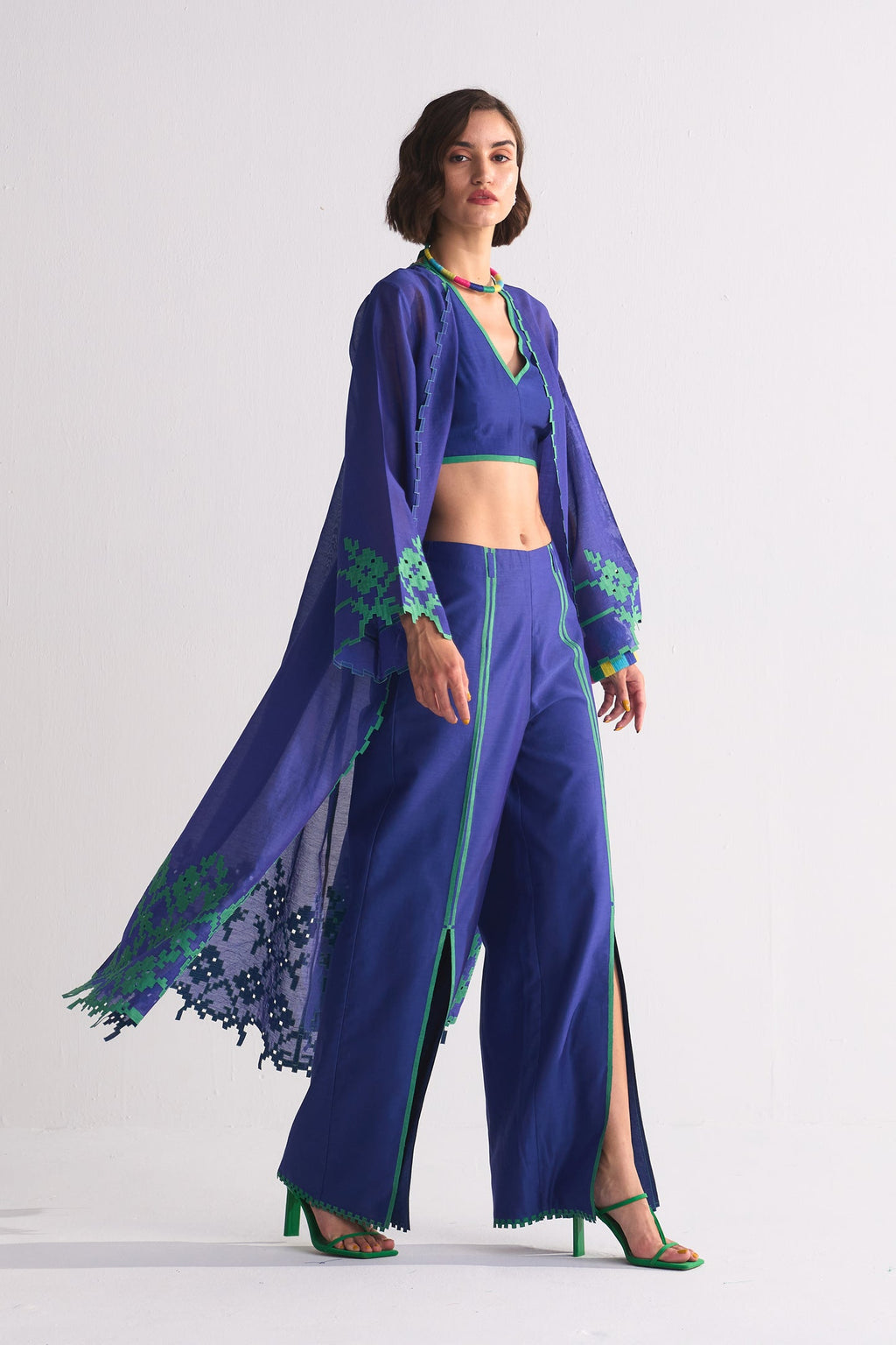 Woman wearing a blue JACKET outfit with green accents on a white background