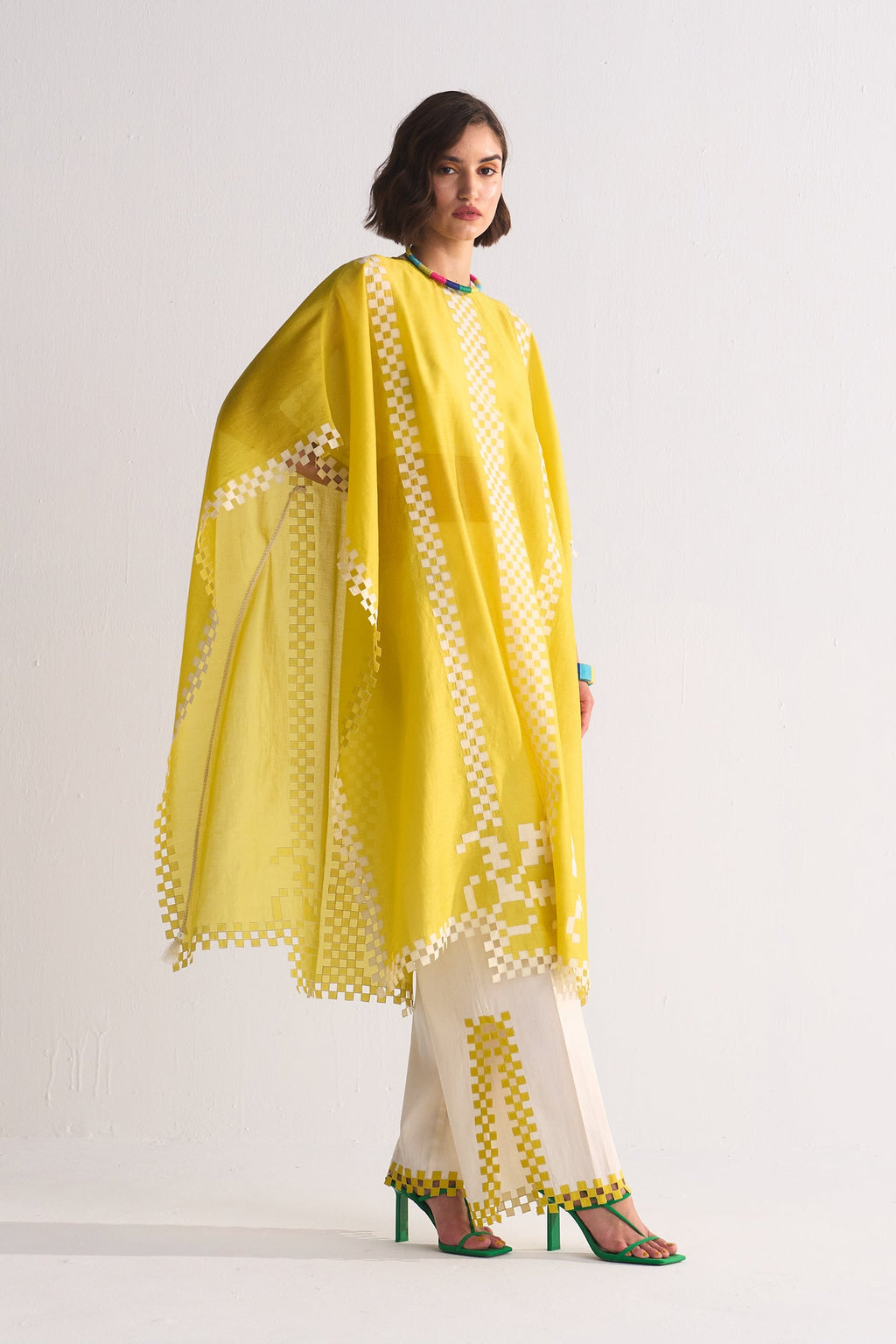 Woman wearing a yellow and white traditional outfit with a matching dupatta on a light gray background