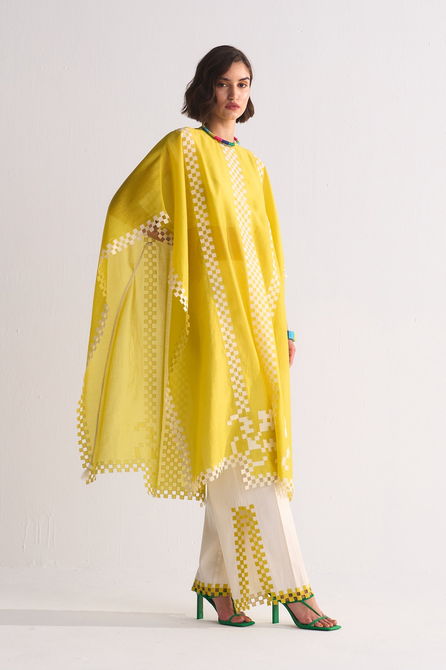 Woman wearing a yellow and white traditional outfit with a matching dupatta on a light gray background