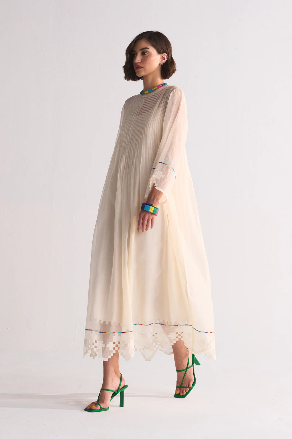 Woman wearing a beige dress with lace details on a white background