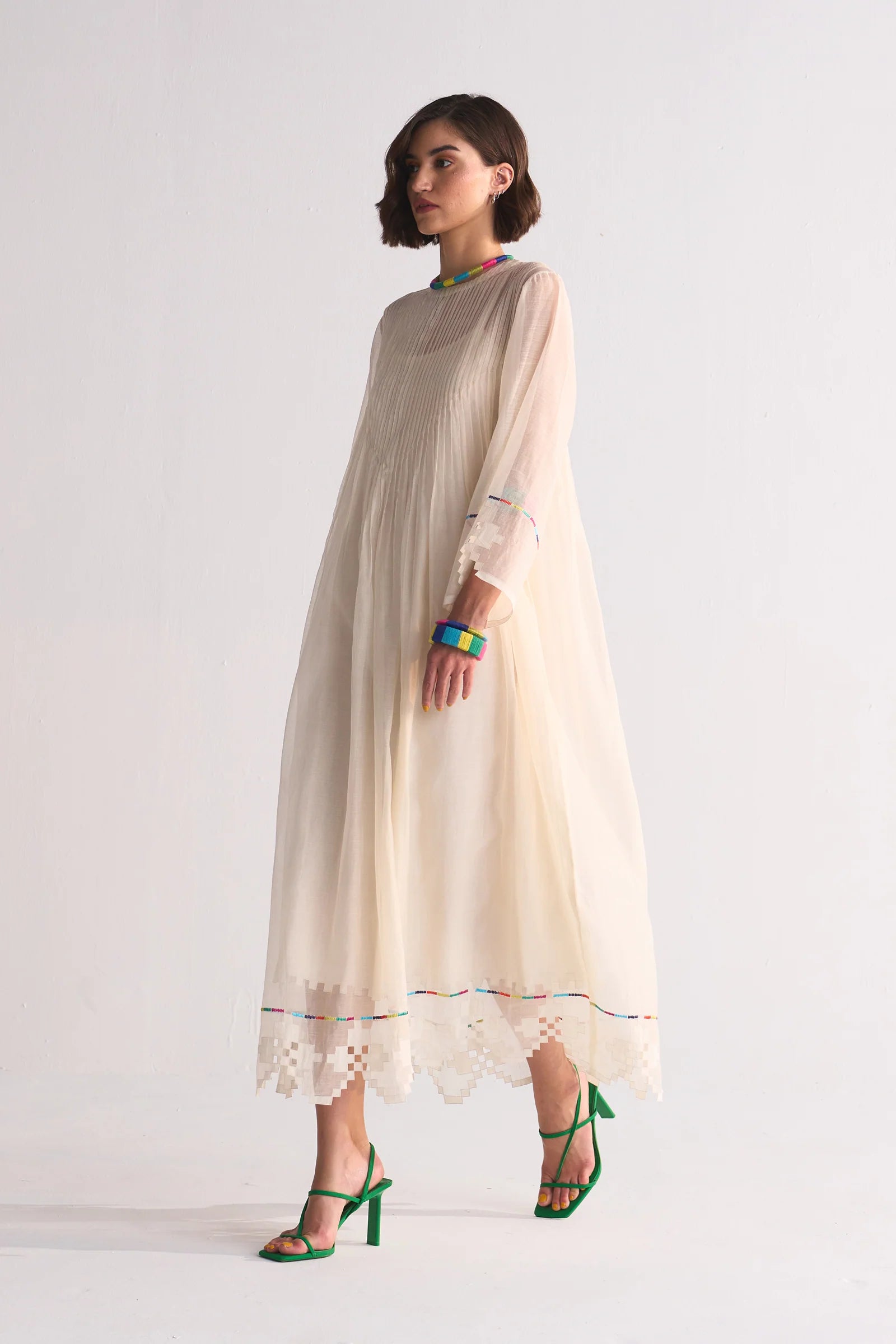 Woman wearing a beige dress with lace details on a white background