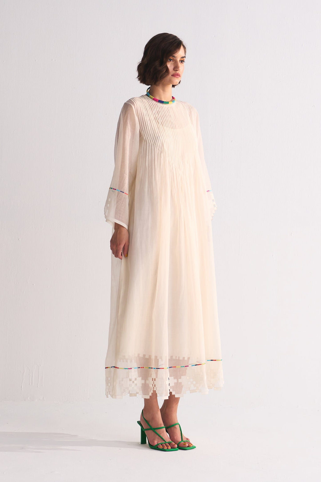 Woman wearing a long, light-colored dress with a white background