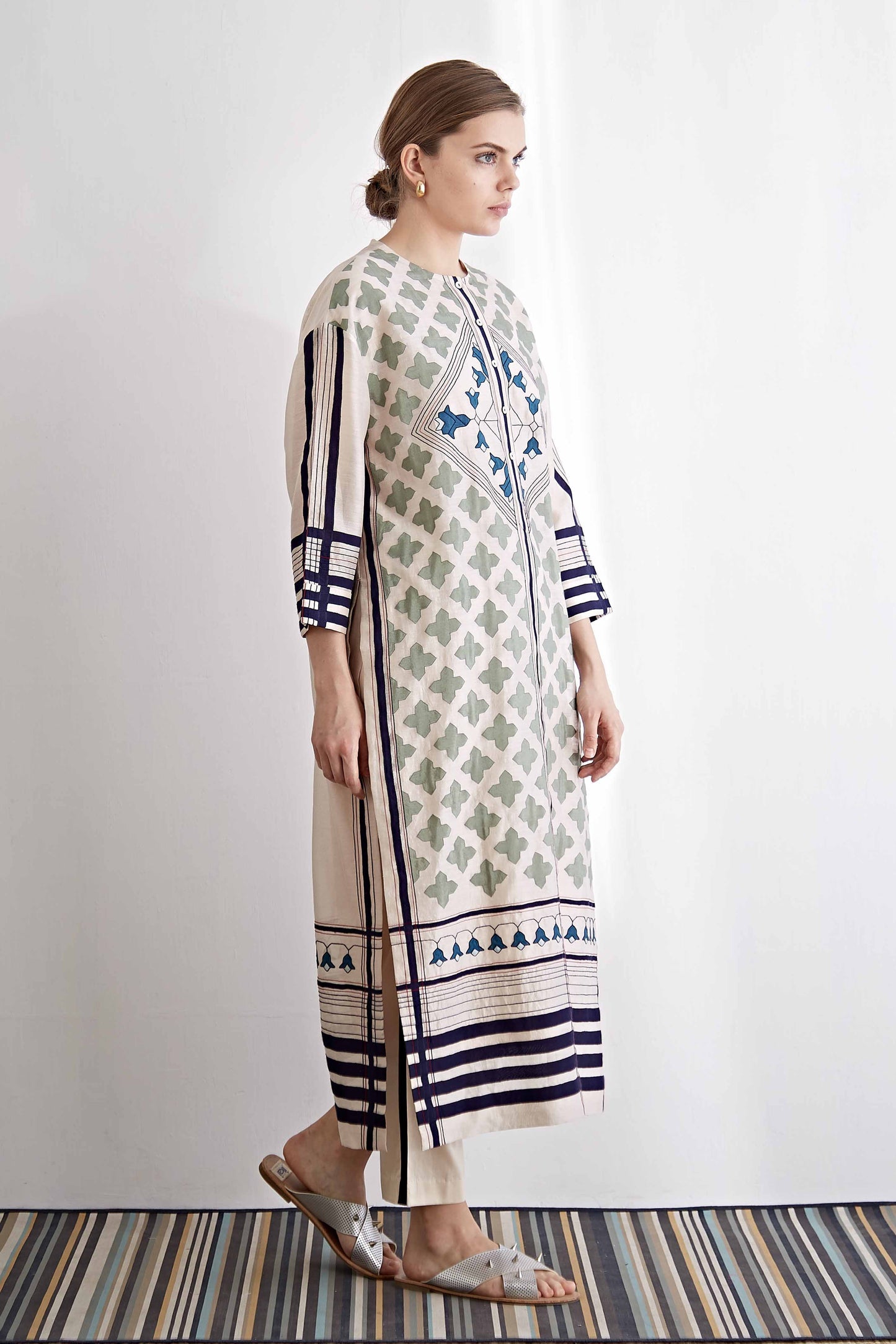 Woman wearing a long, patterned dress with a white background