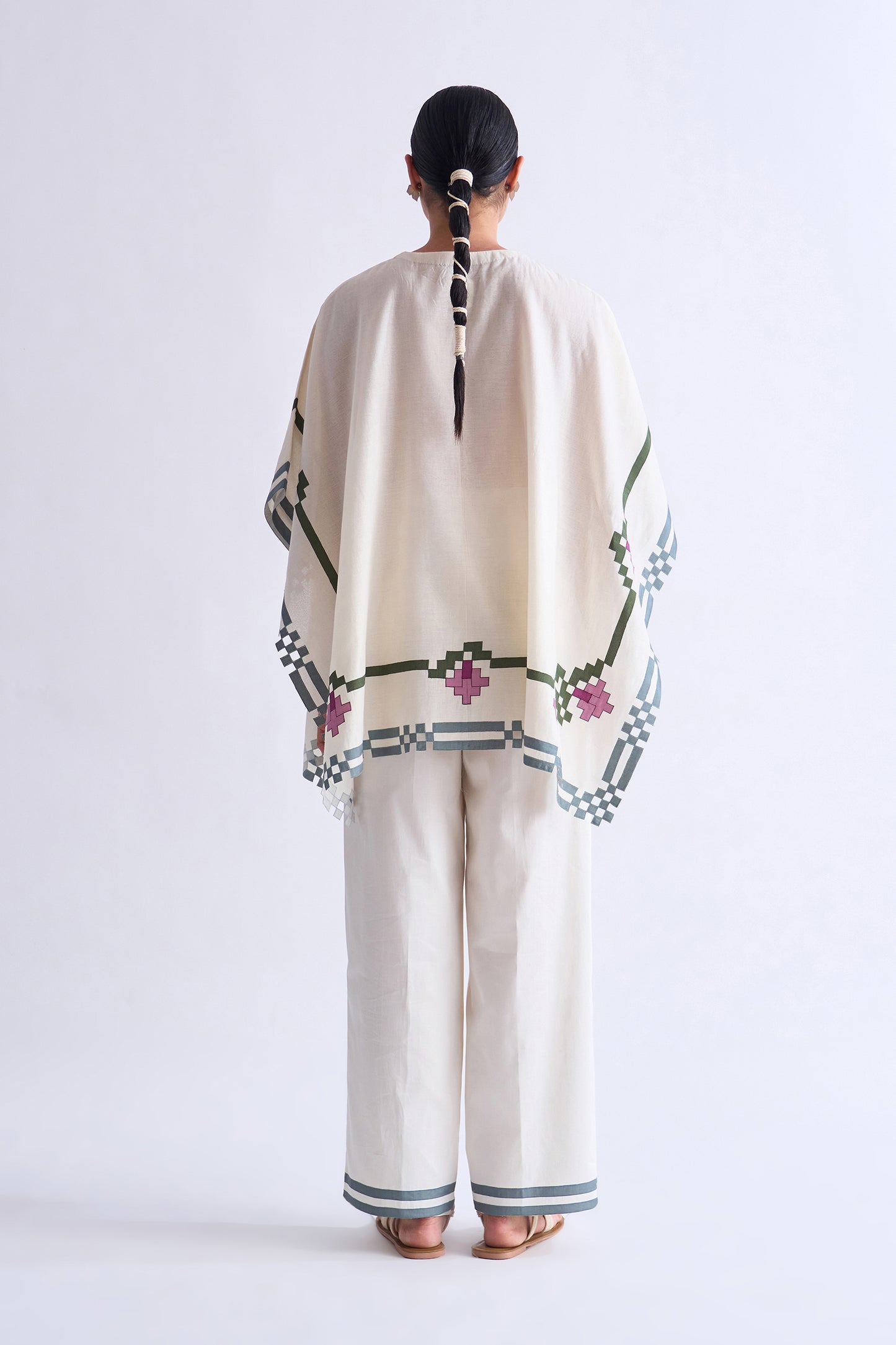 Person wearing a traditional outfit with floral patterns on a white background