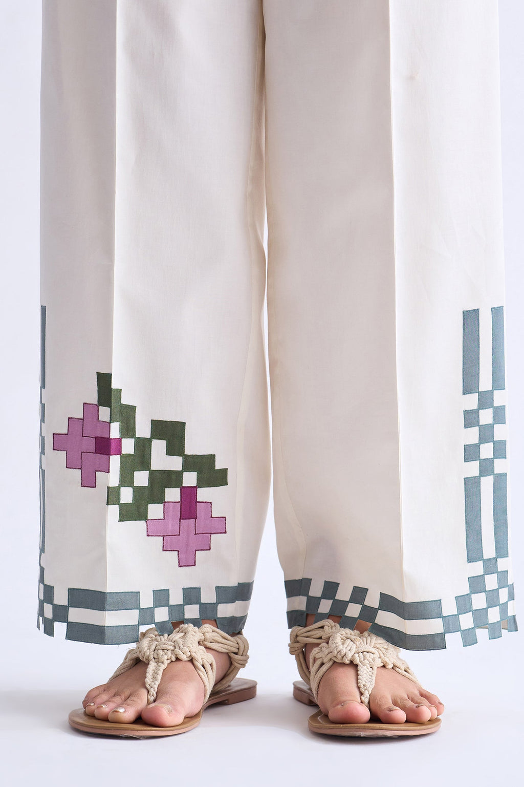 White pants with geometric patterns and sandals on a white background