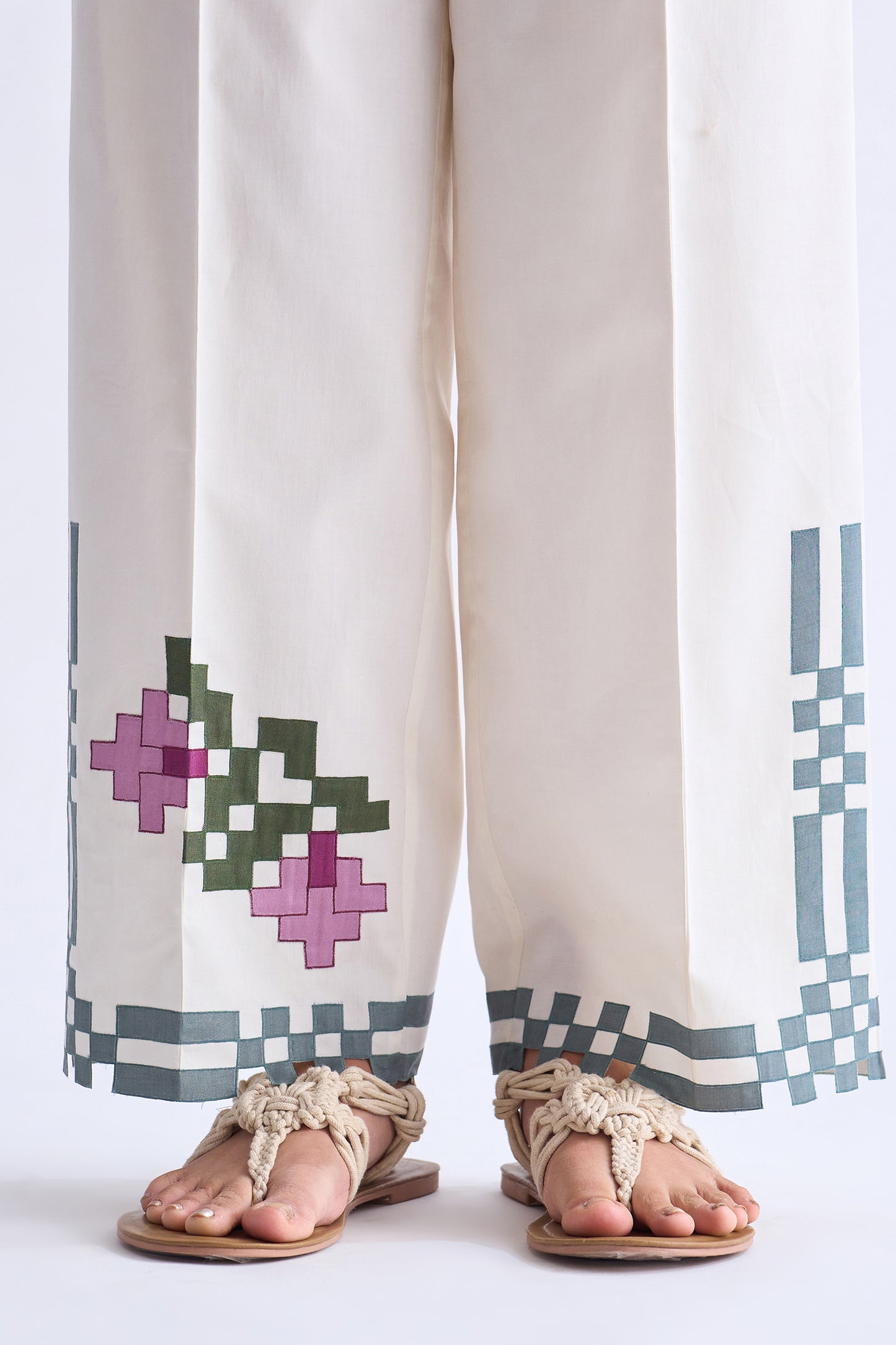White pants with geometric patterns and sandals on a white background