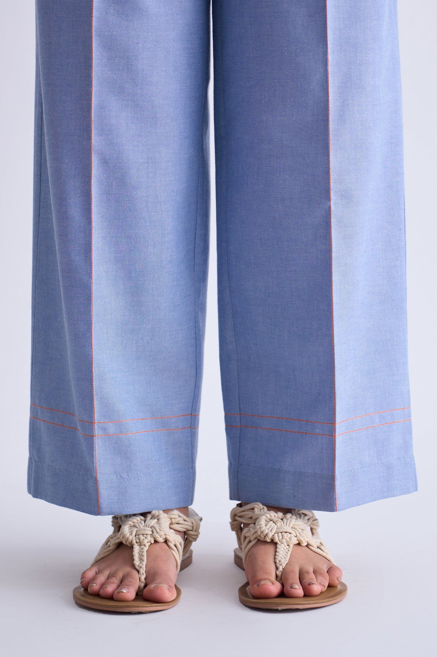 Light blue pants with red stitching worn by a person on a white background