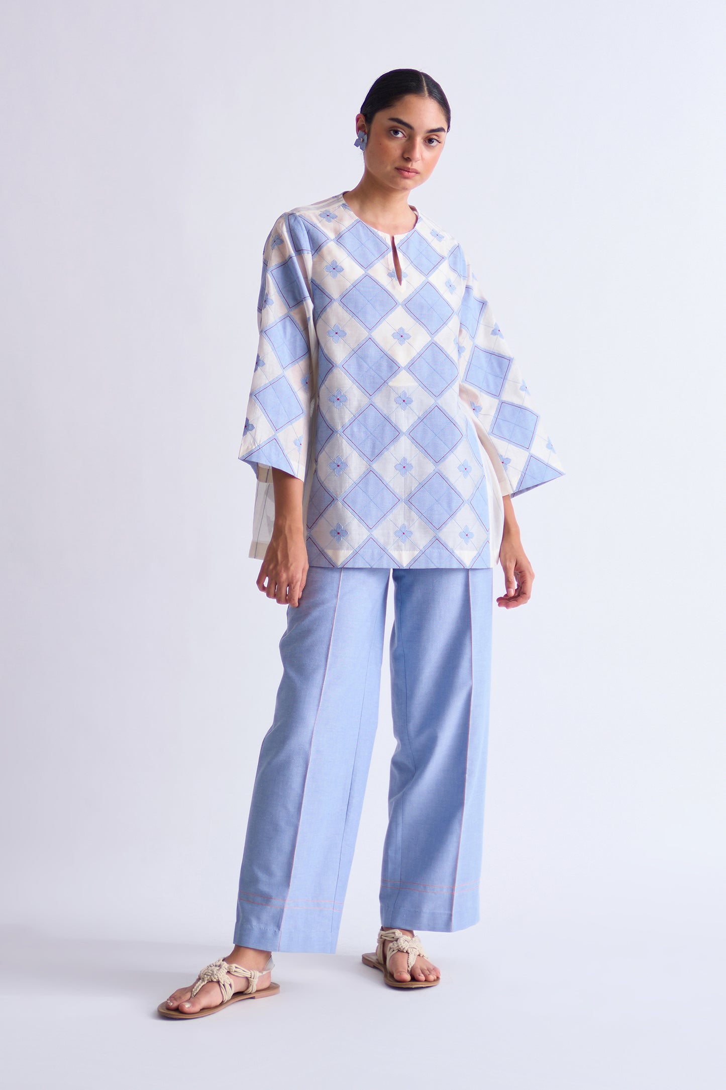 Woman wearing a blue and white checkered top with matching pants on a white background