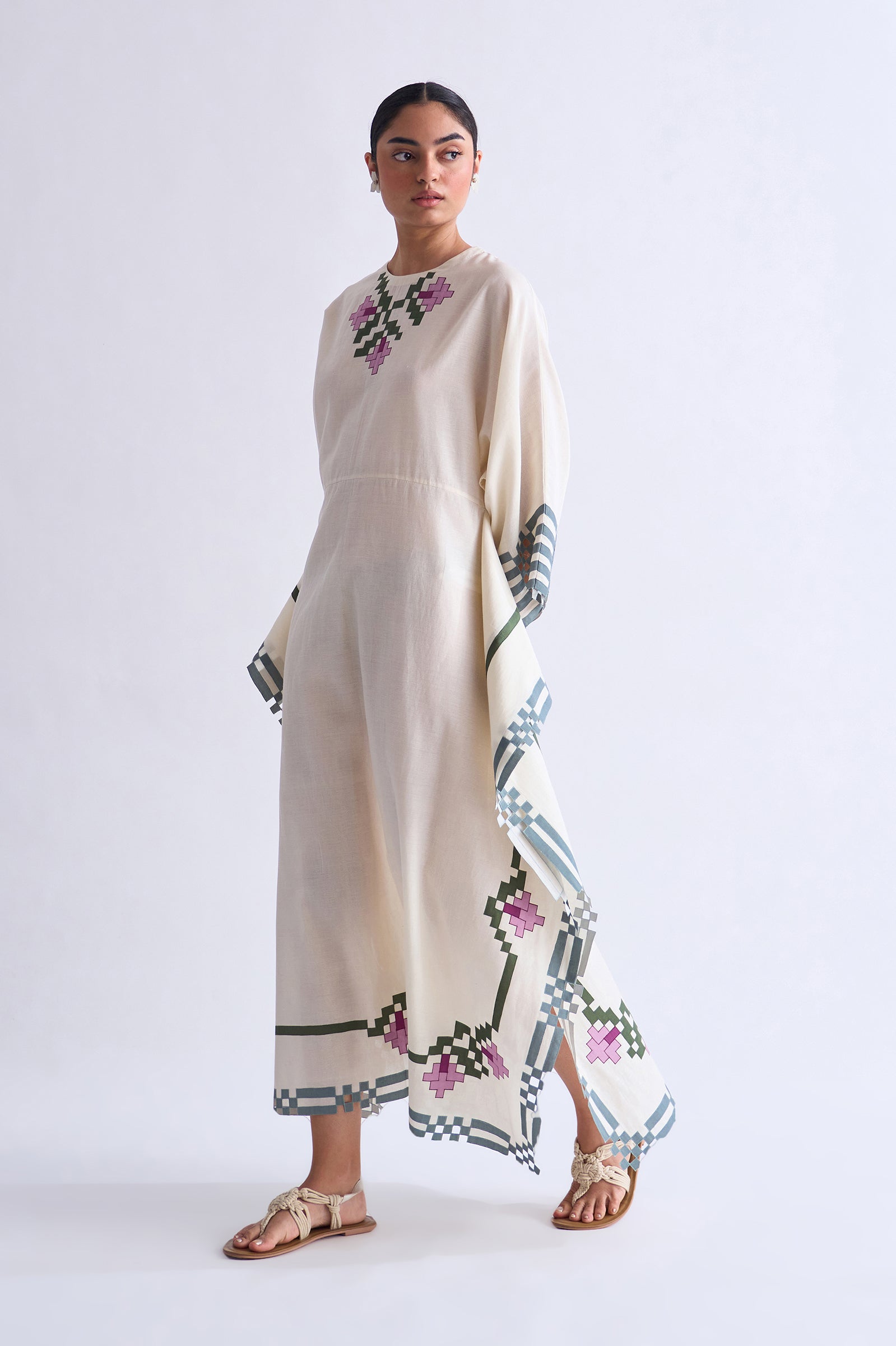 Woman wearing a beige dress with floral embroidery on a white background