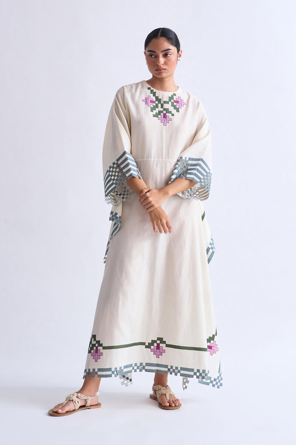 Woman wearing a long, embroidered dress on a white background
