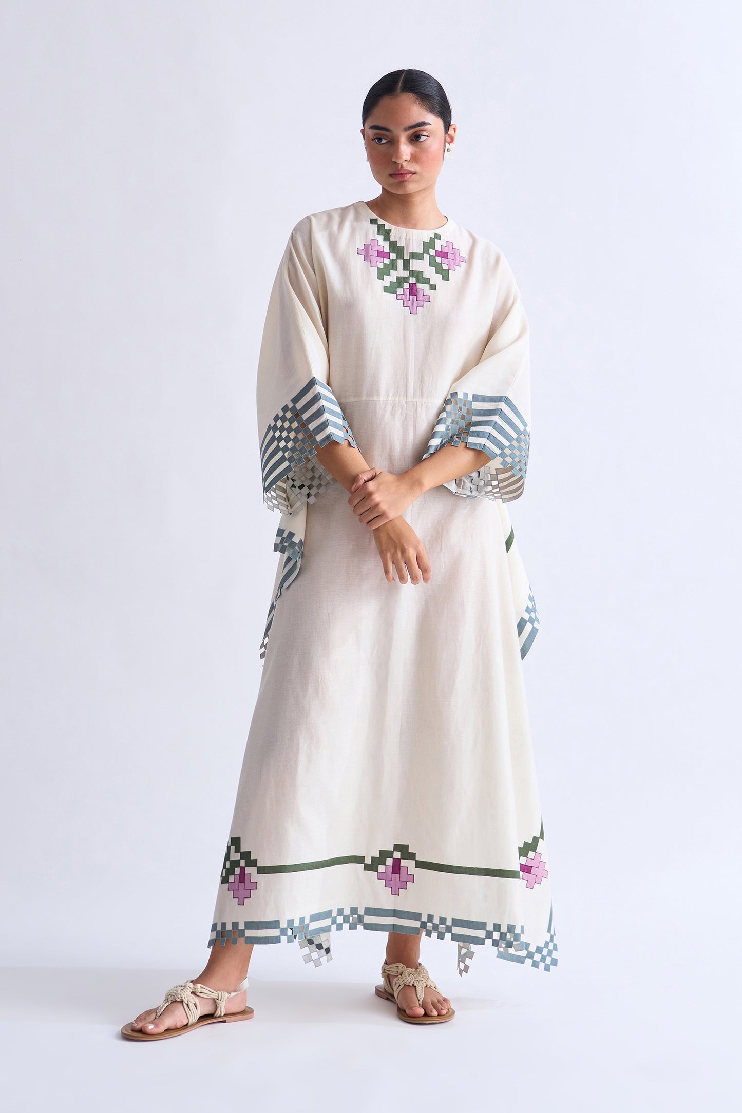 Woman wearing a long, embroidered dress on a white background