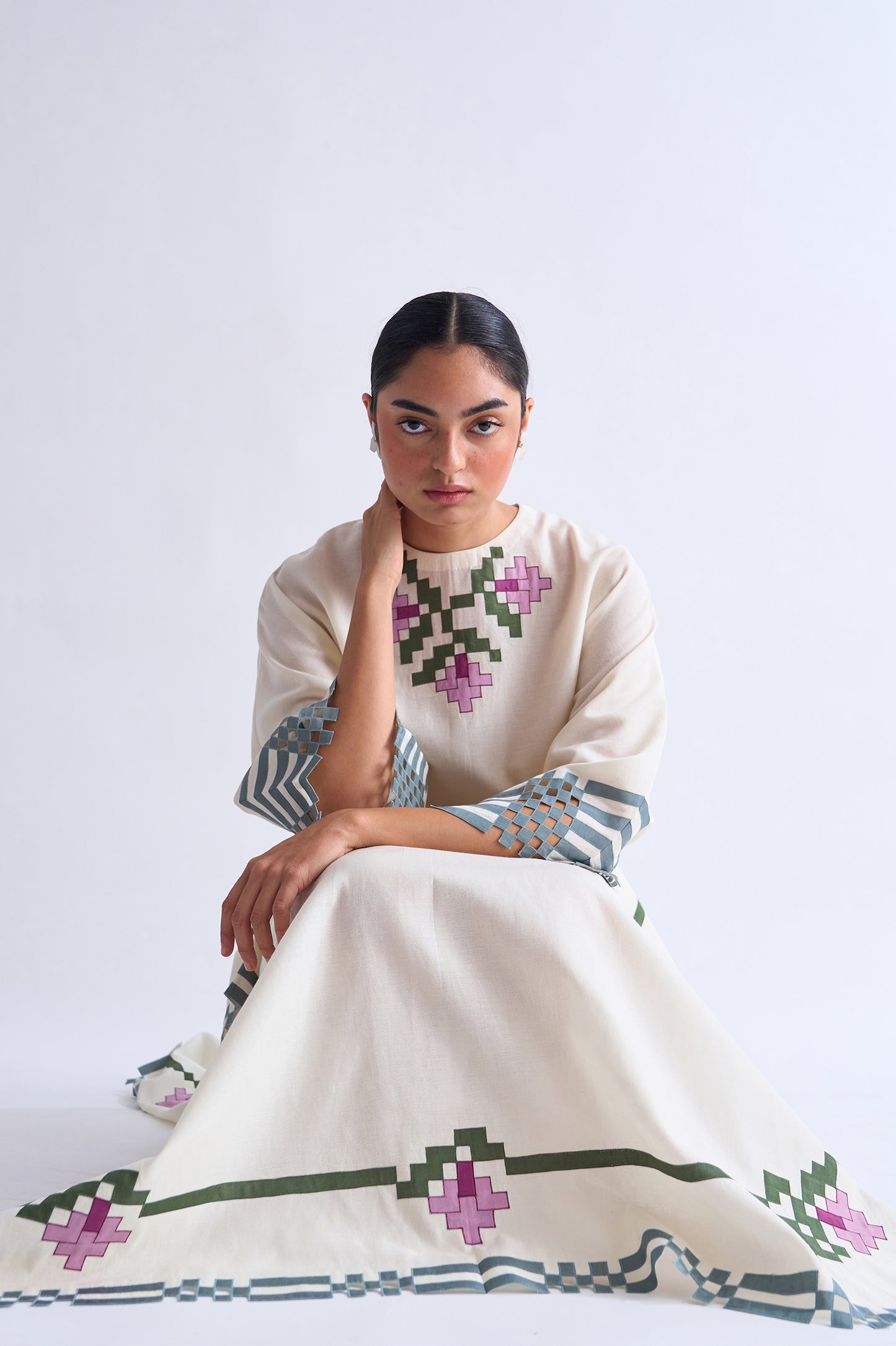 Woman wearing a traditional embroidered dress with a white background