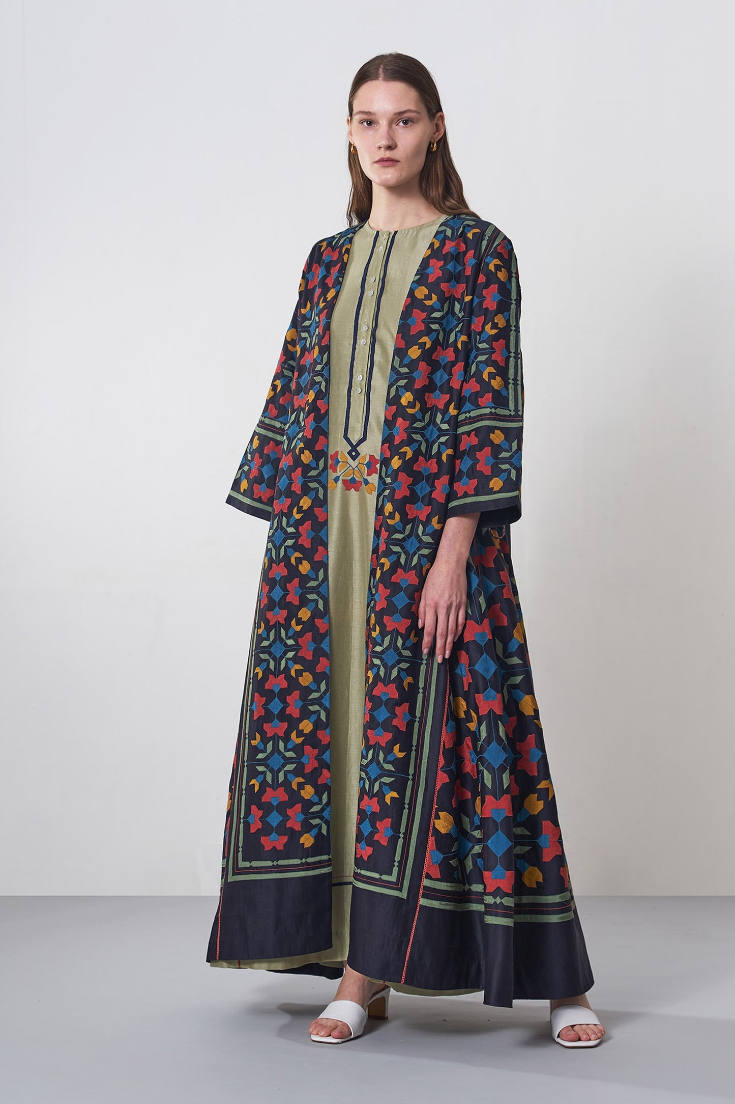 Woman wearing a long, patterned dress with a neutral background