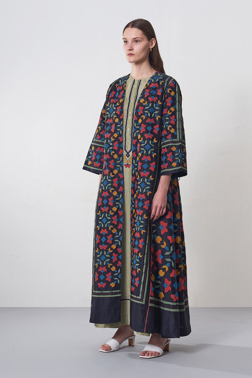 Woman wearing a colorful patterned dress against a white background