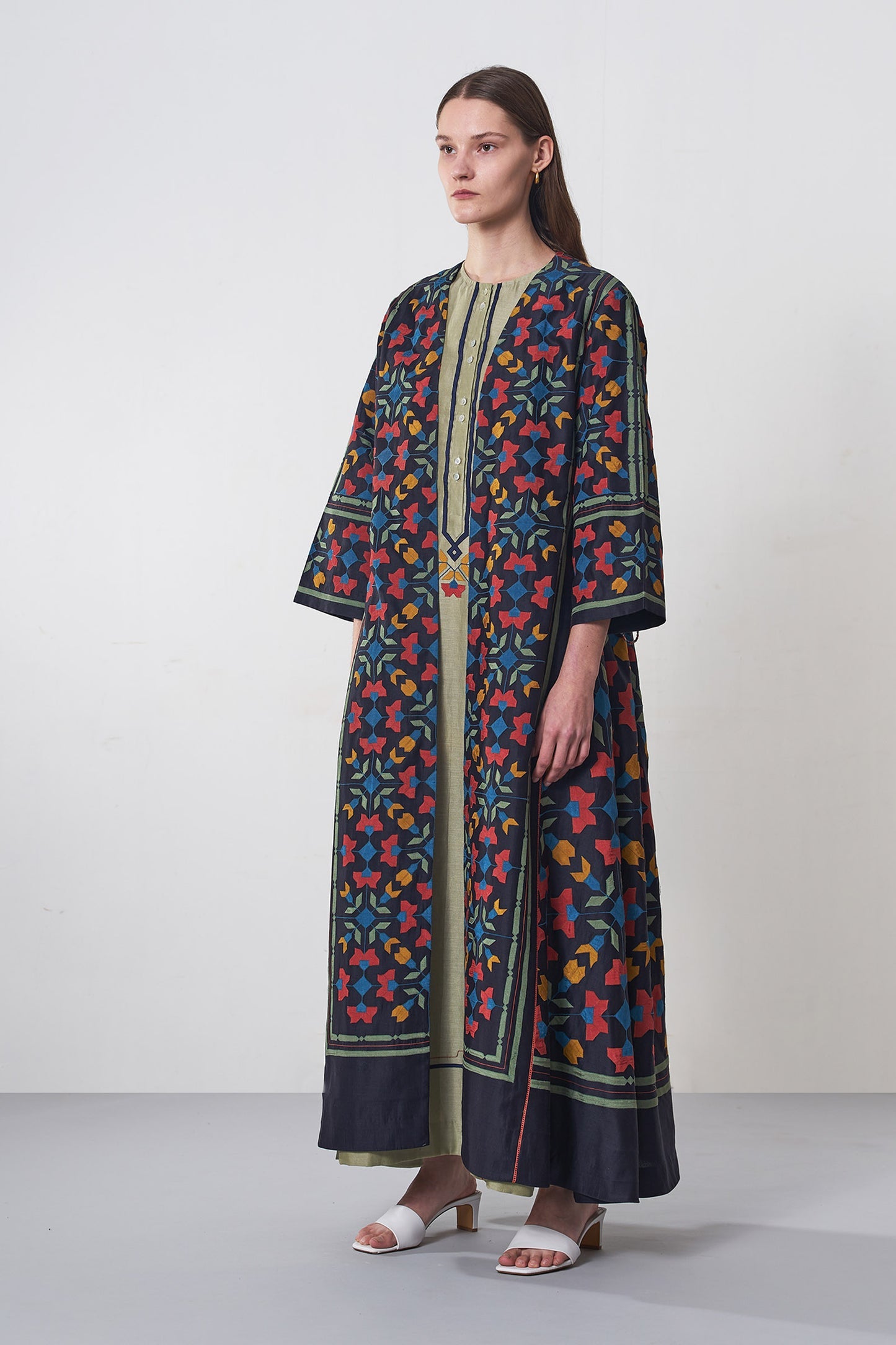 Woman wearing a colorful patterned dress against a white background