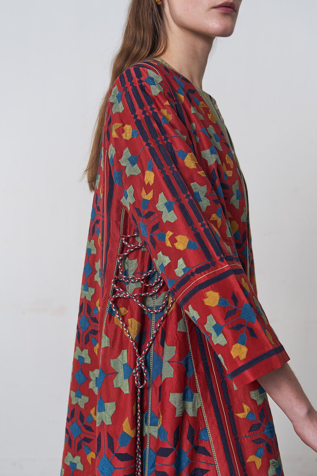 Woman wearing a colorful patterned dress with a plain background