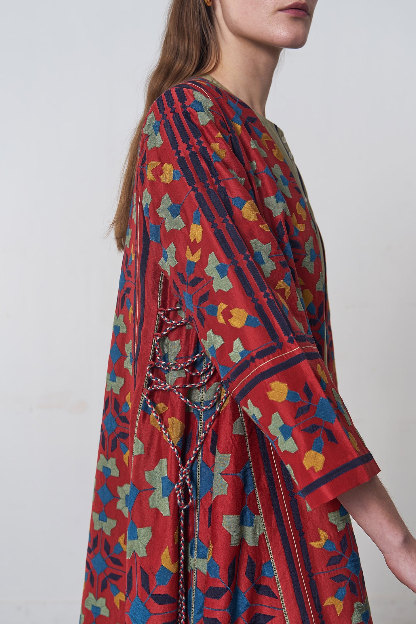 Woman wearing a colorful patterned dress with a plain background