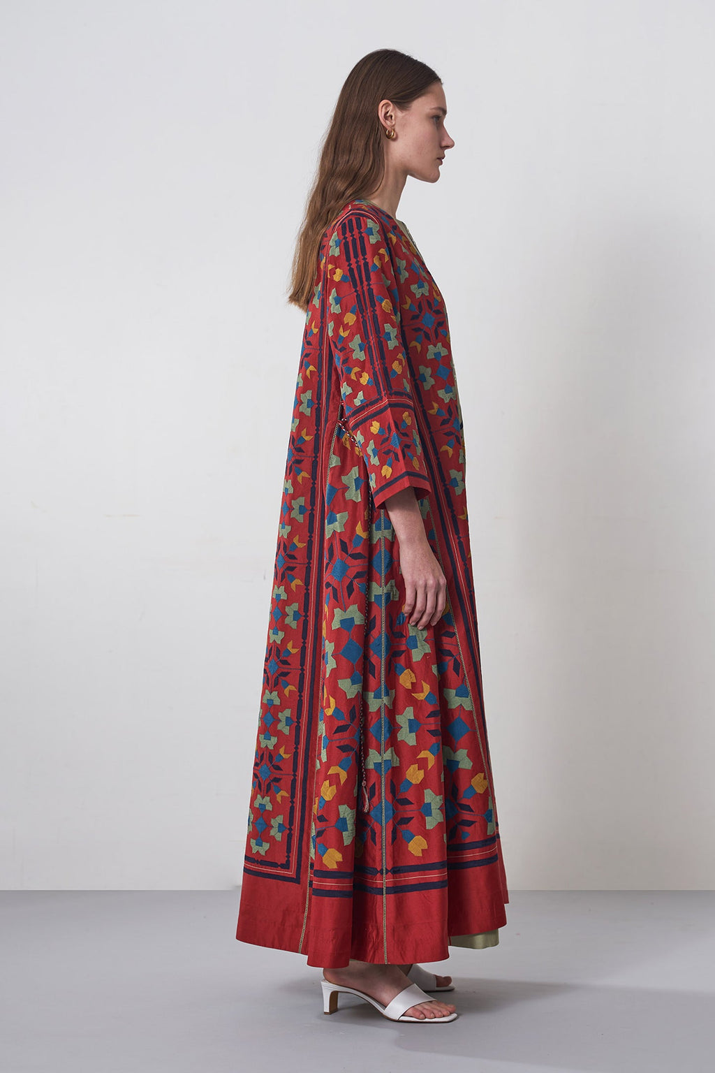 Woman wearing a colorful dress with a pattern on a plain background