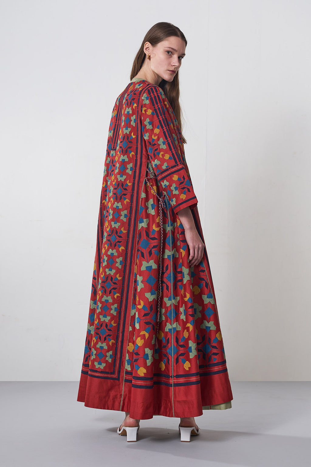 Woman wearing a long, patterned dress with a neutral background