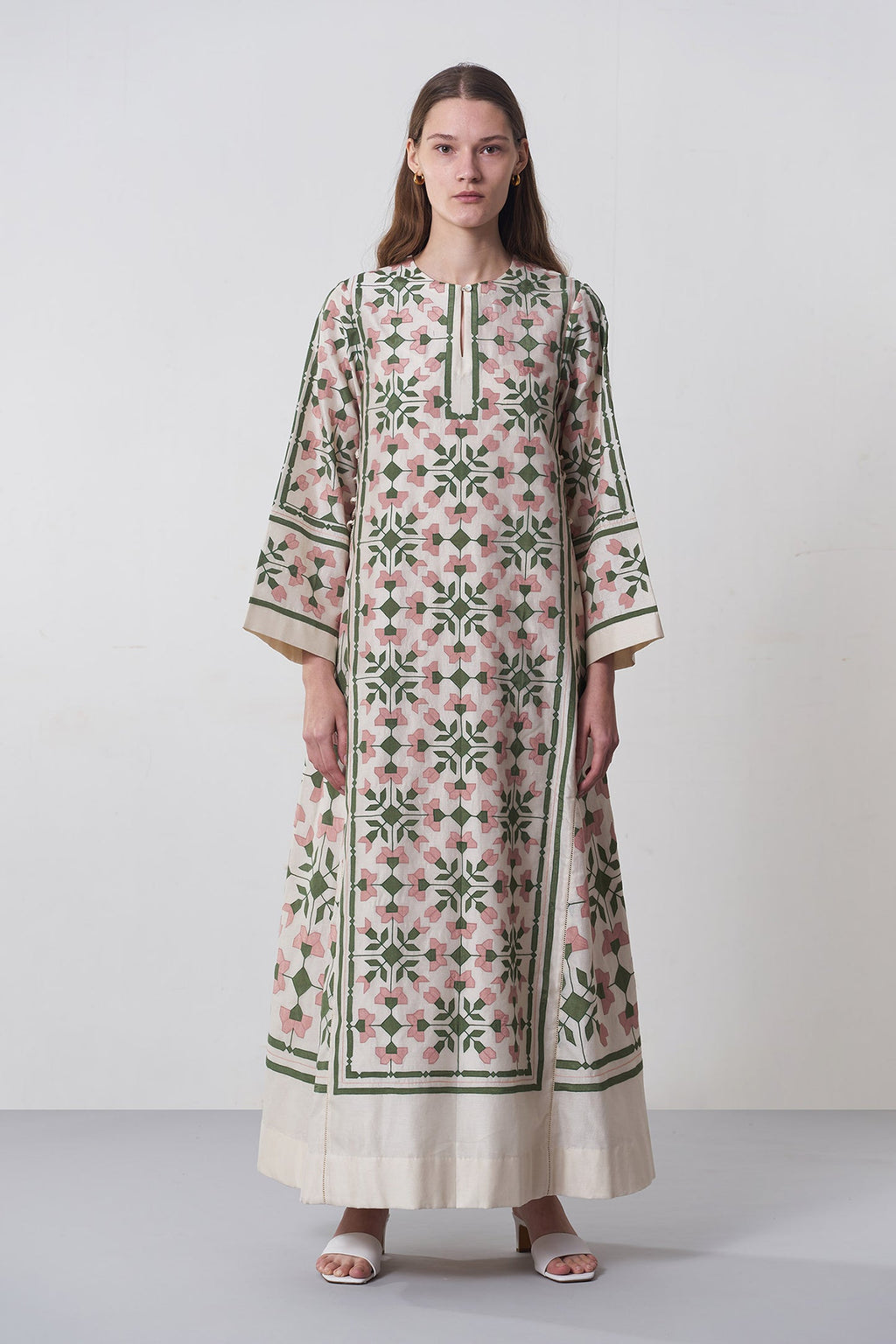 Woman wearing a long, patterned dress against a white background