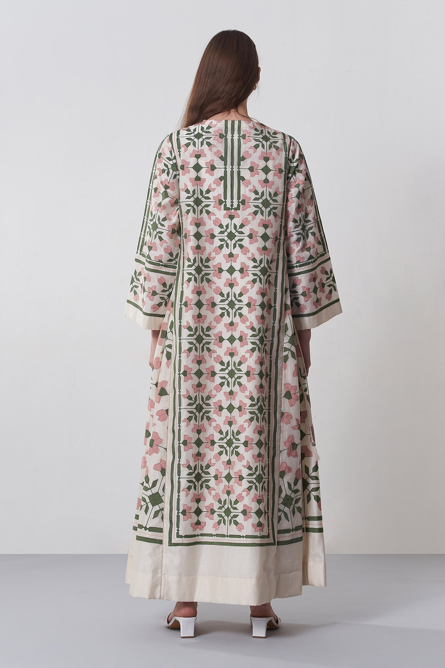 Woman wearing a long, patterned dress with a white background