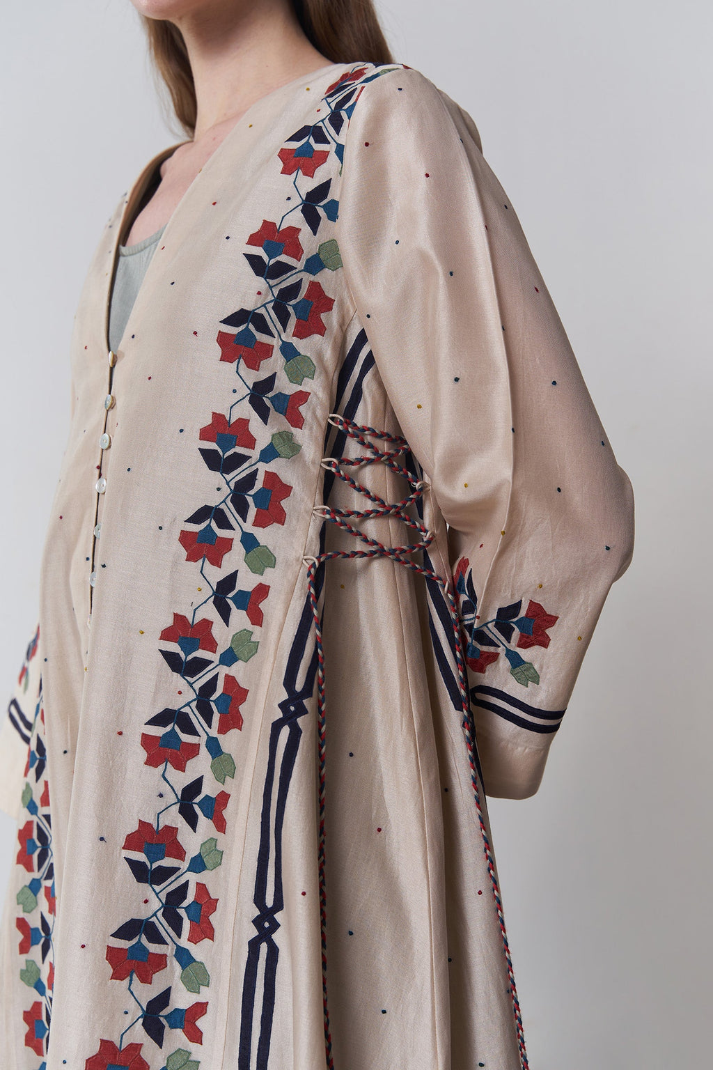 Beige dress with colorful floral embroidery on a plain background