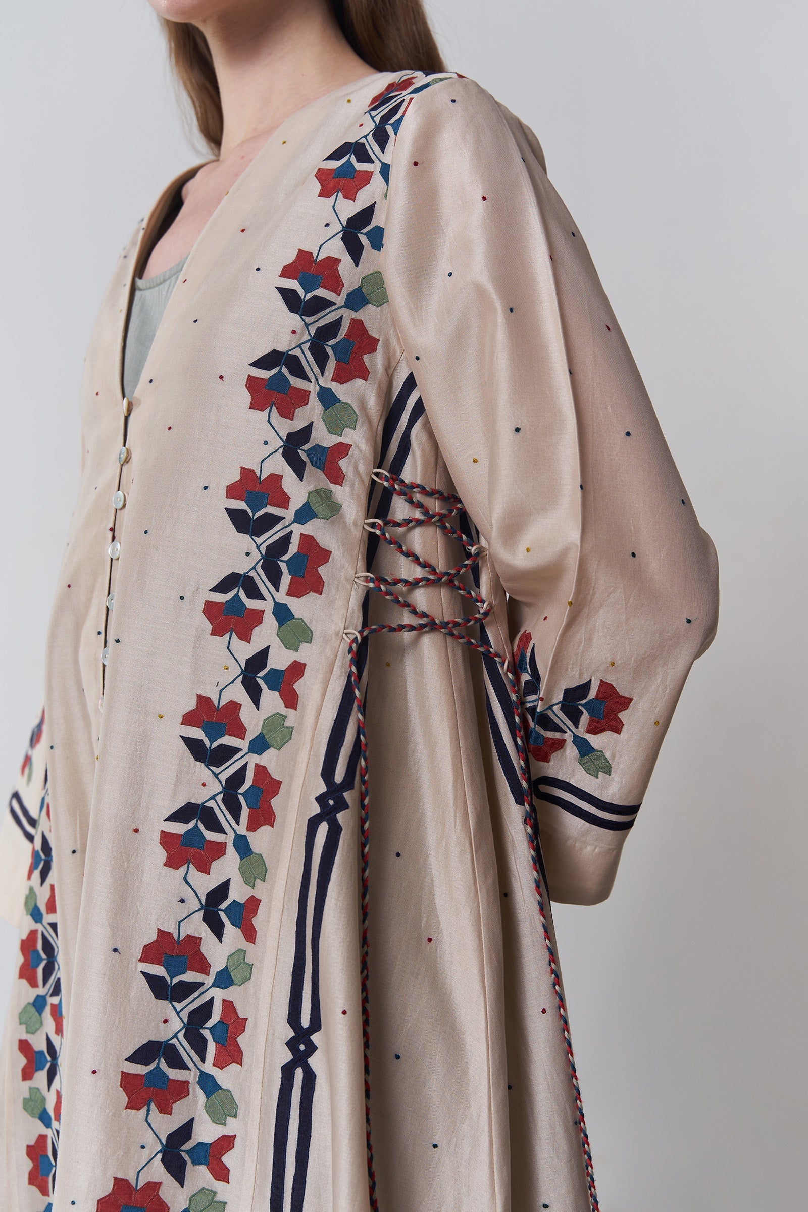 Beige dress with colorful floral embroidery on a plain background