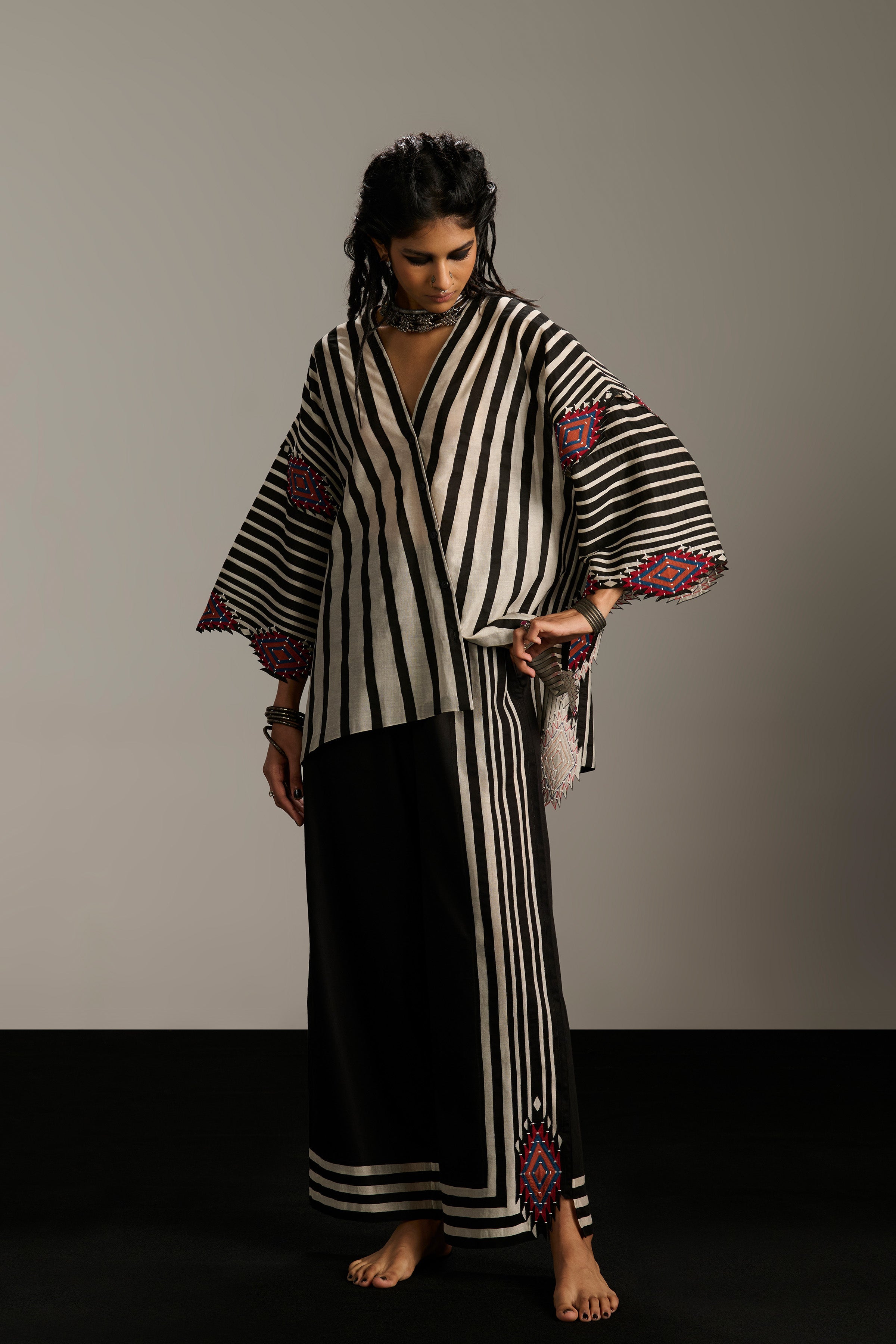 Woman wearing a black and white striped outfit with purple accents on a plain background