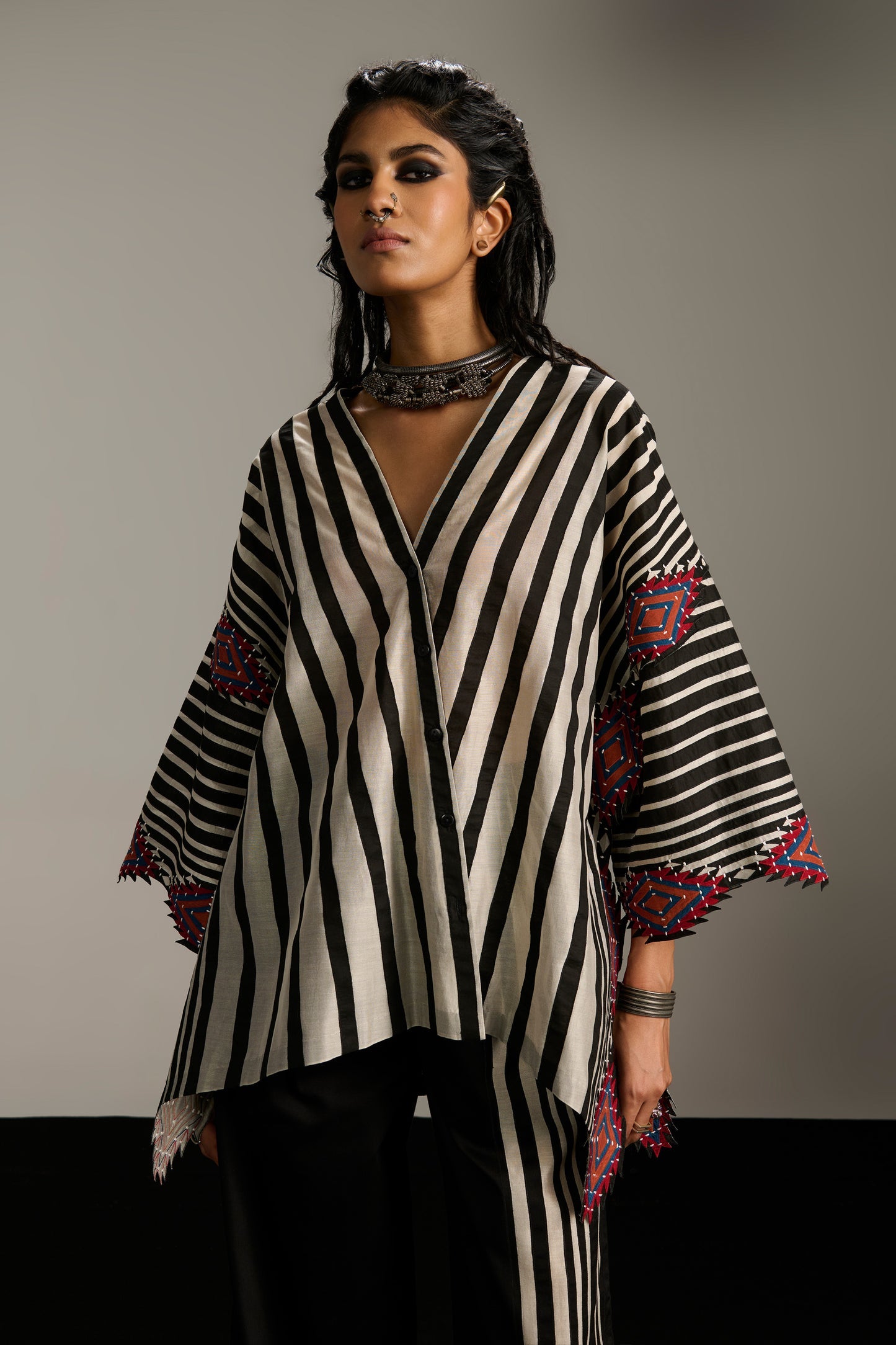 Woman wearing a black and white striped outfit with red patterns on a gray background