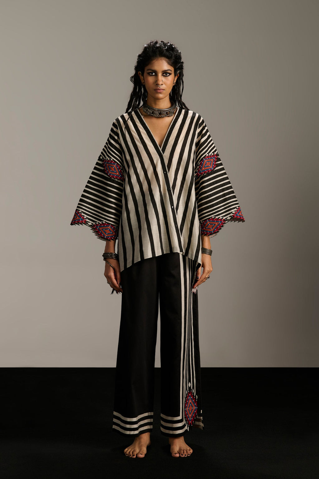 Woman wearing a black and white striped outfit with red accents against a plain background